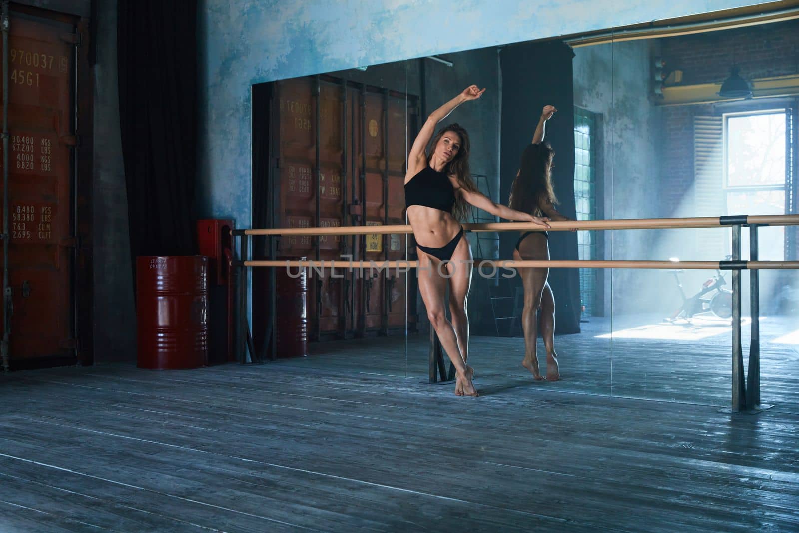 a beautiful girl of athletic build, a ballerina stands at a ballroom dancing machine in a large loft-style gym, a huge mirrored wall, daylight from the window by vladimirdrozdin