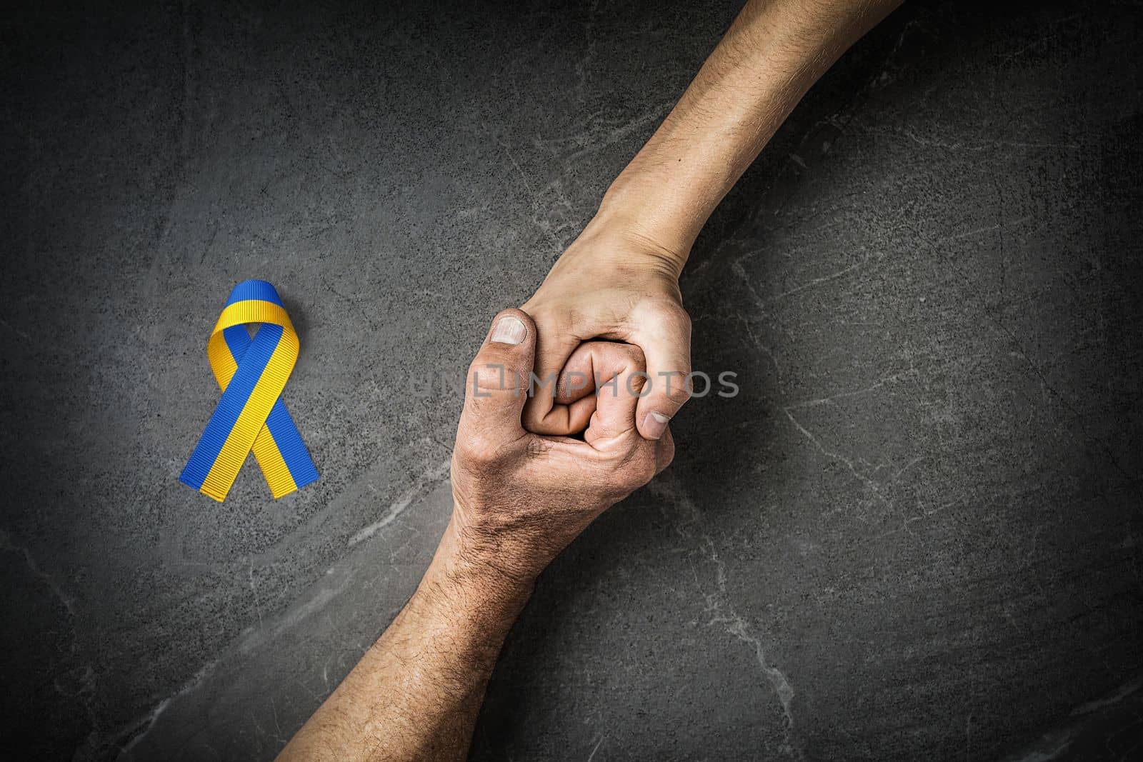 adult hand holding tight hand of child with yellow and blue ribbon. concept needs help and support, truth will win