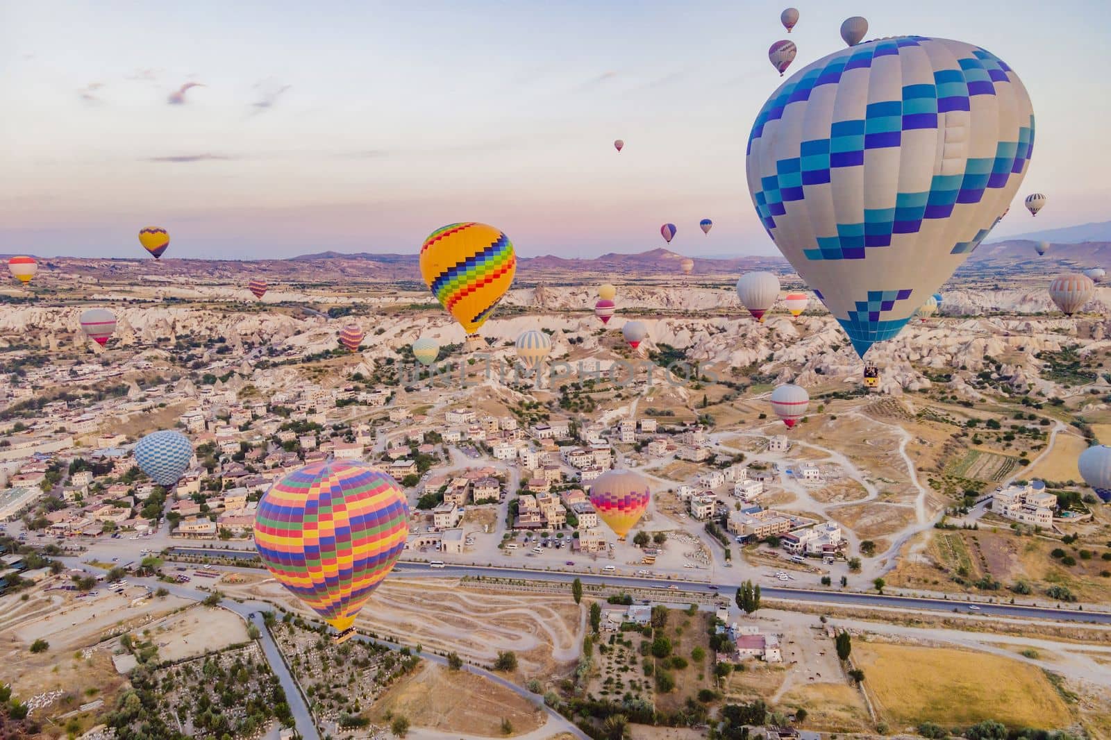 Colorful hot air balloons flying over at fairy chimneys valley in Nevsehir, Goreme, Cappadocia Turkey. Spectacular panoramic drone view of the underground city and ballooning tourism. High quality.
