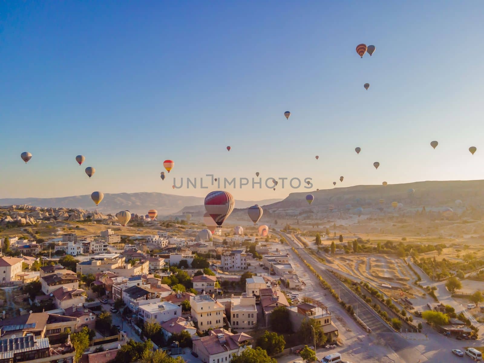 Colorful hot air balloons flying over at fairy chimneys valley in Nevsehir, Goreme, Cappadocia Turkey. Spectacular panoramic drone view of the underground city and ballooning tourism. High quality.