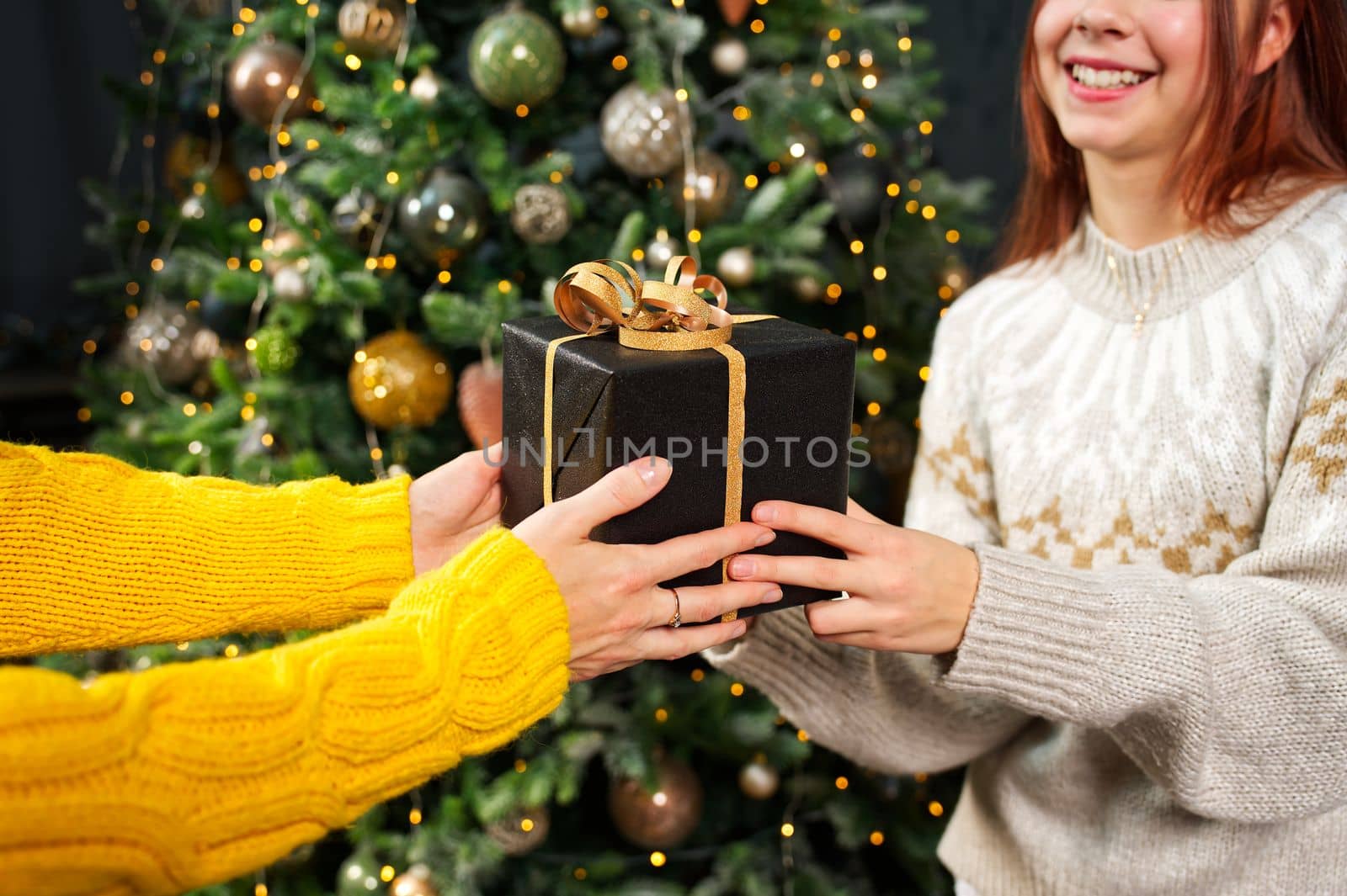 Smiling mother gives her daughter a christmas present. Happy family sharing joy with each other. Christmas day at home. Merry Christmas and Happy Holidays. Christmas holiday celebration