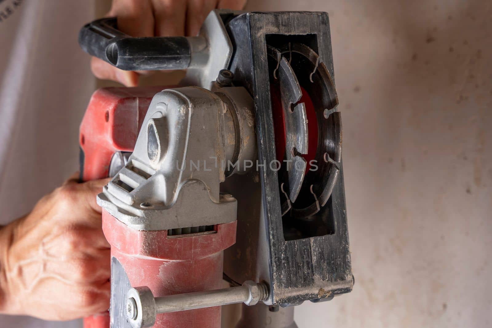 professional construction power tool for cutting grooves in concrete in the hands of a worker during the renovation of the apartment. A hand-held power tool with two diamond discs for cutting grooves in the wall for laying electrics. Professional tool. Close-up