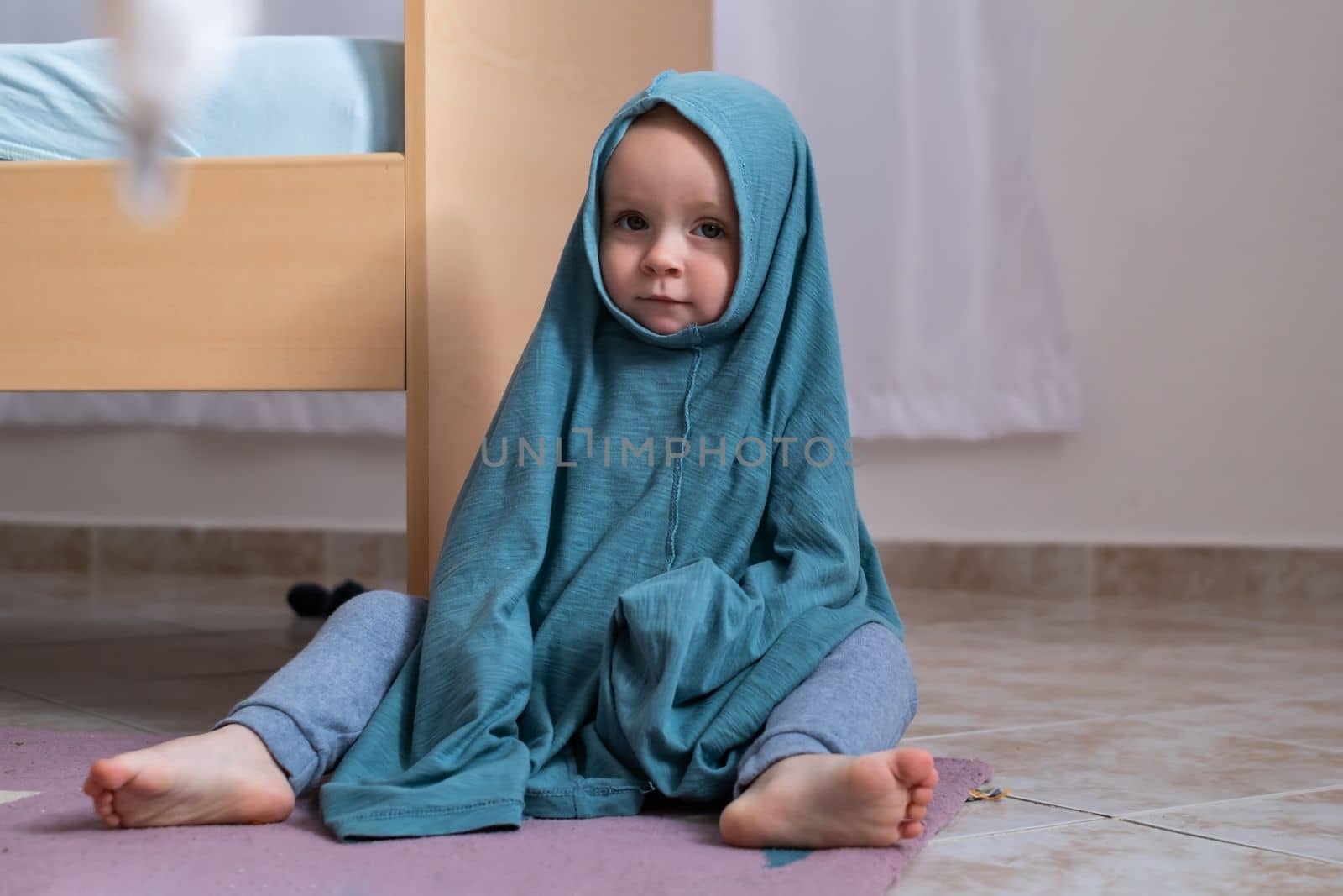 Cute caucasian baby girl dressing herself at her mother t-shirt.