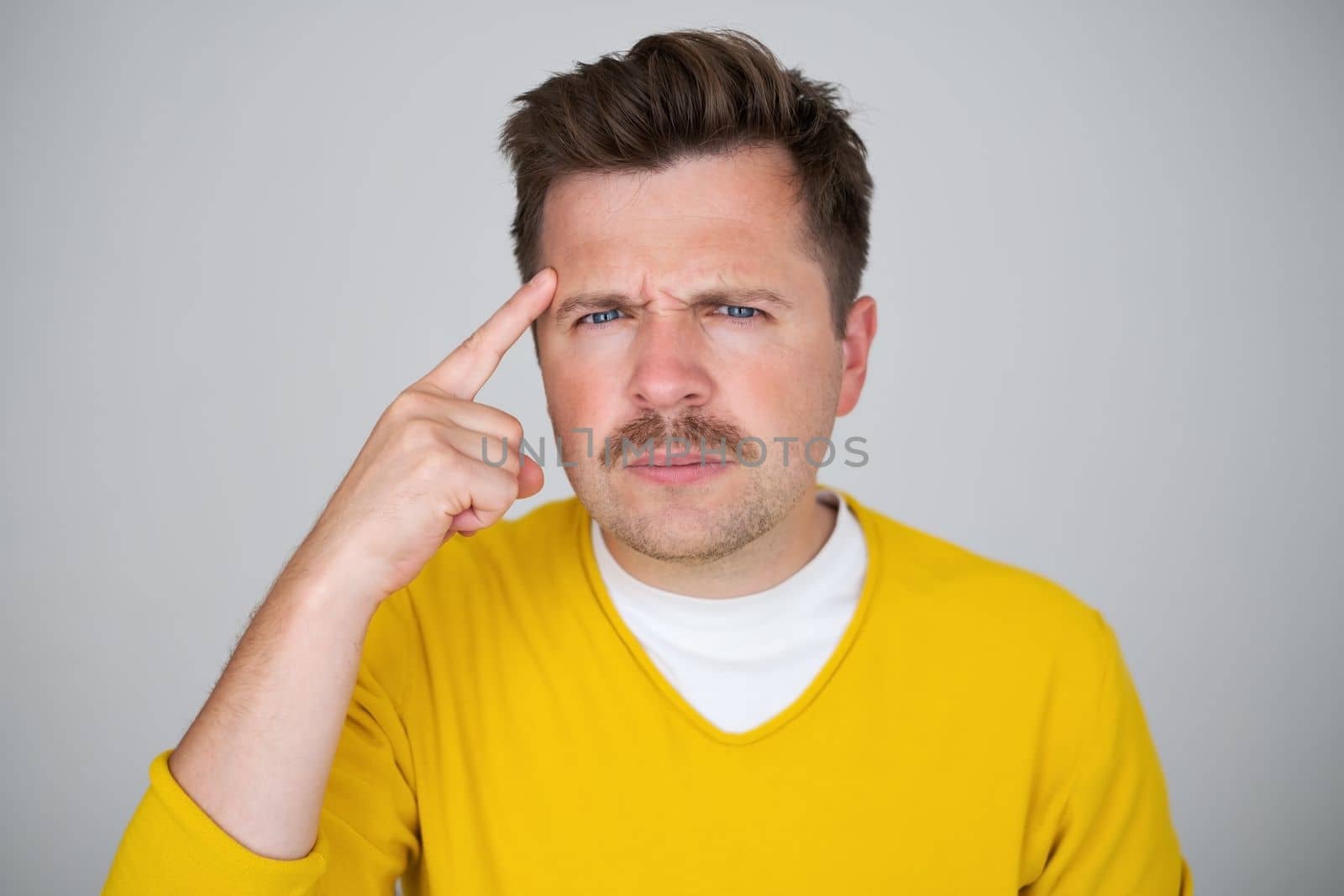 Pensive curious man wearing yellow sweater in thinking pose trying to make choice or decision 