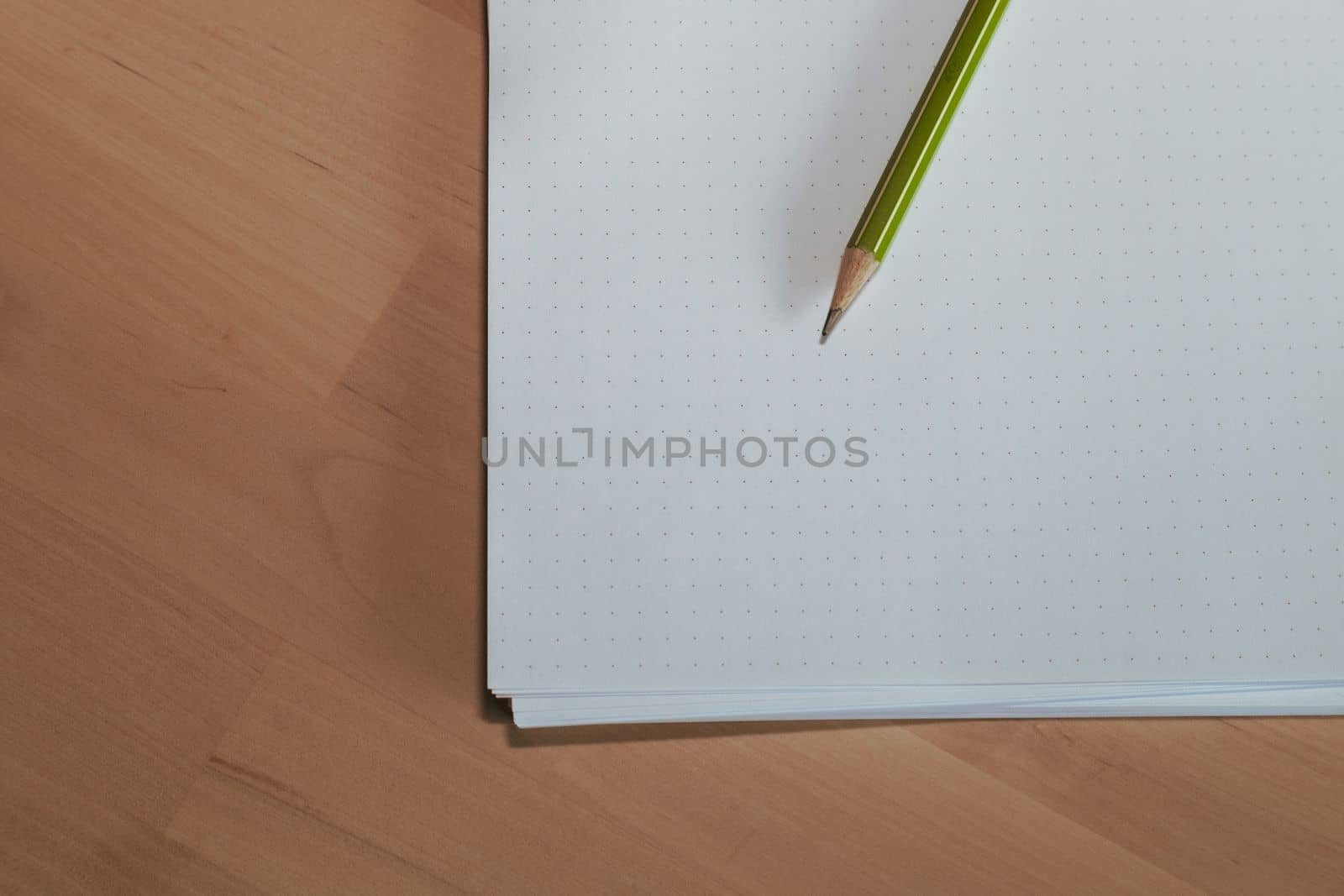 Paper sheet with a pencil on wooden table. Pencil on table, the blogger instrument