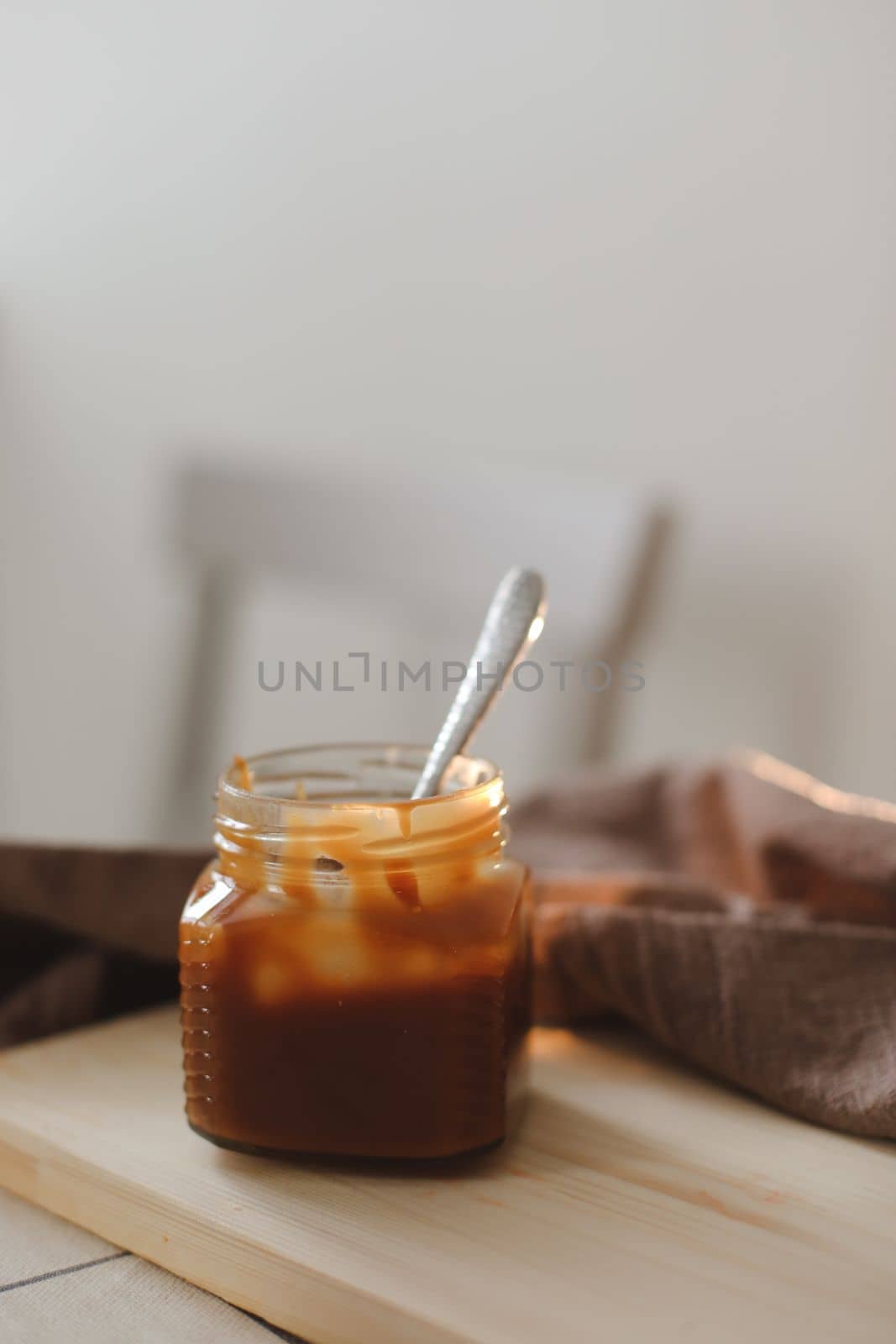 Homemade salted caramel sauce in jar on rustic wooden table