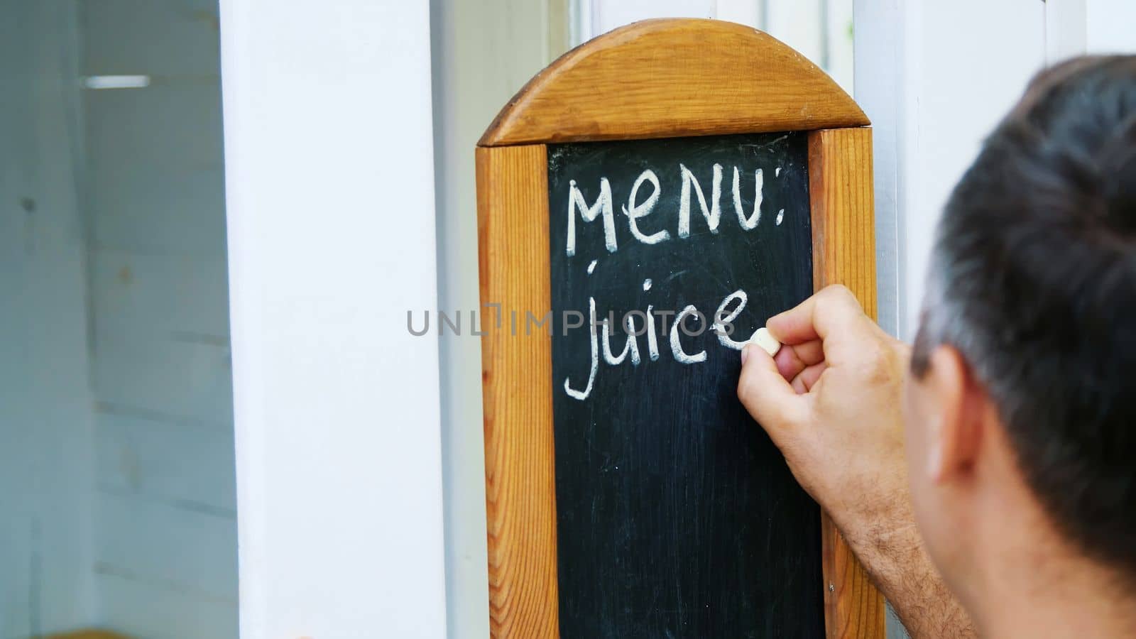 close-up, on blackboard man writing with white chalk, words-menu, juice. High quality photo