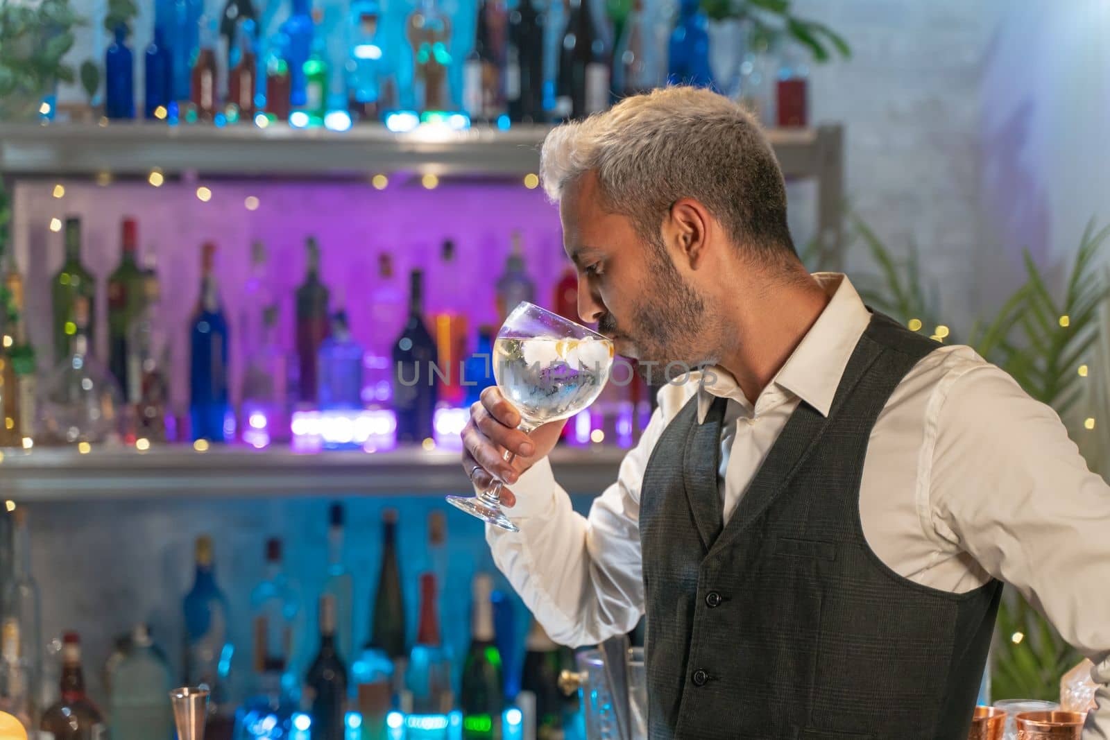 Professional barman tasting cocktail in nightclub. Night life concept. High quality photo