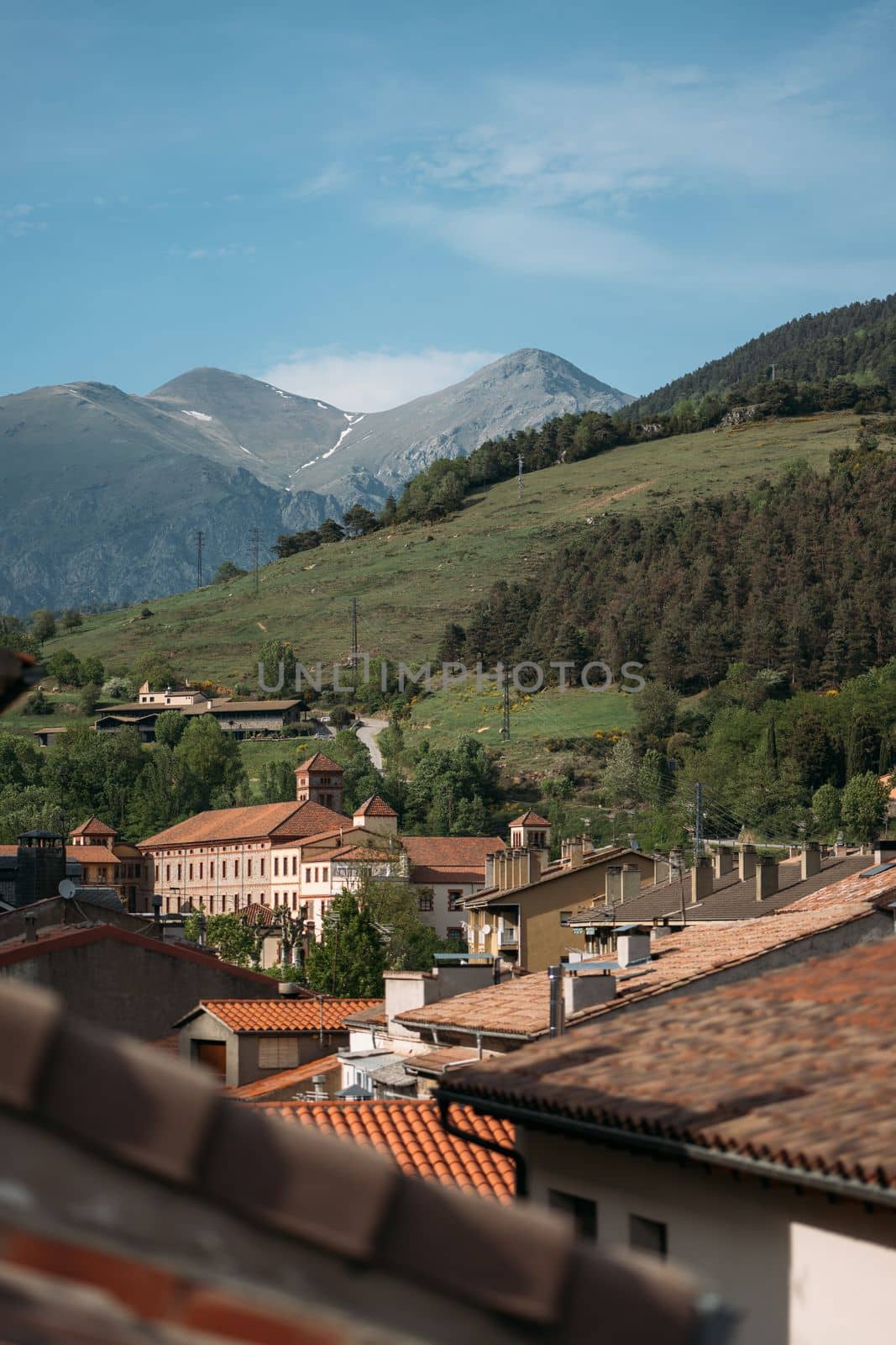 Orange roofs of modern houses in small village of Ribes de Freser at foot of Pyrenees in Spain. Sunlight illuminates beautiful village with picturesque mountain nature and beautiful architecture