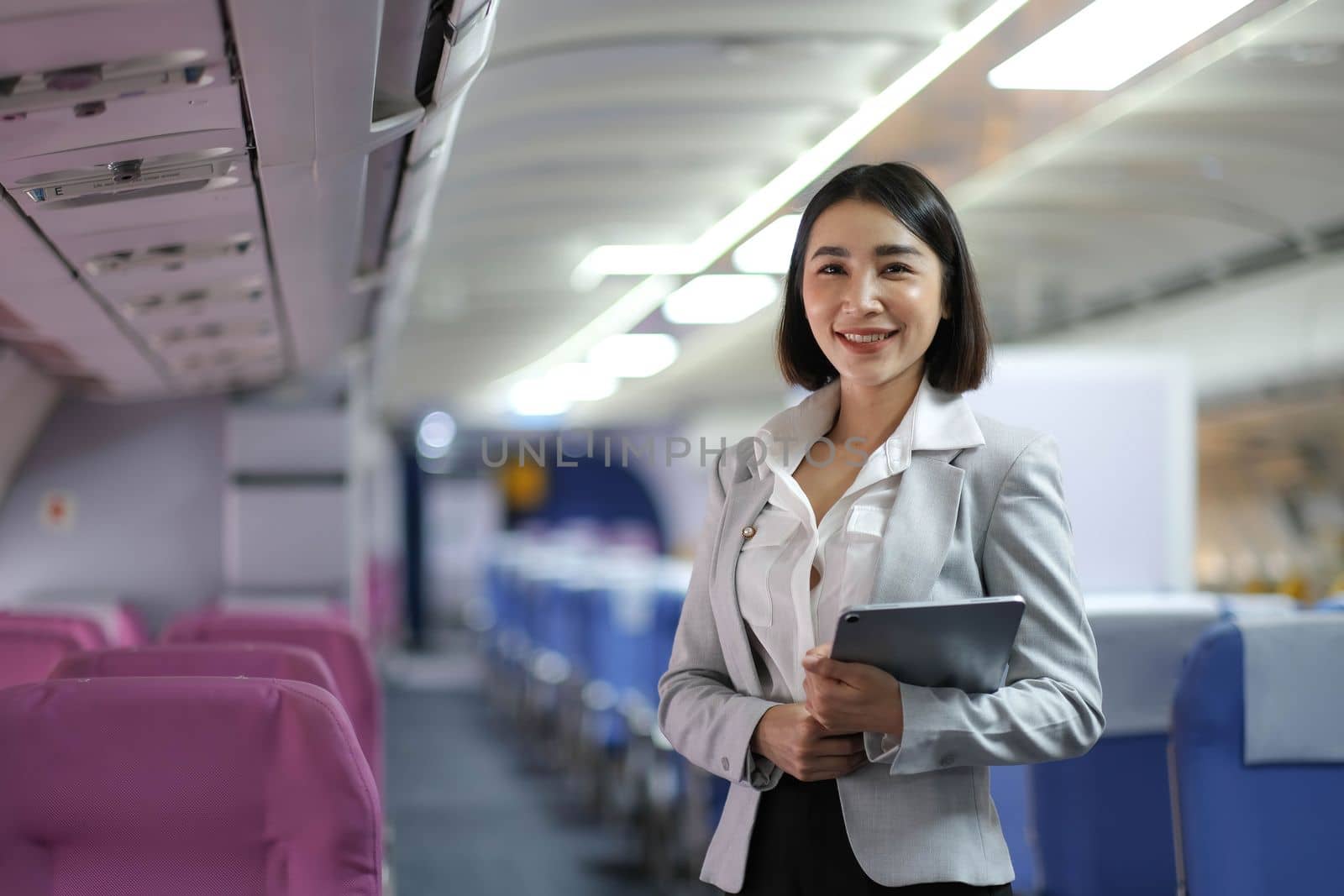 Attractive caucasian female passenger of airplane sitting in comfortable seat while working at modern laptop computer with mock up area using wireless connection