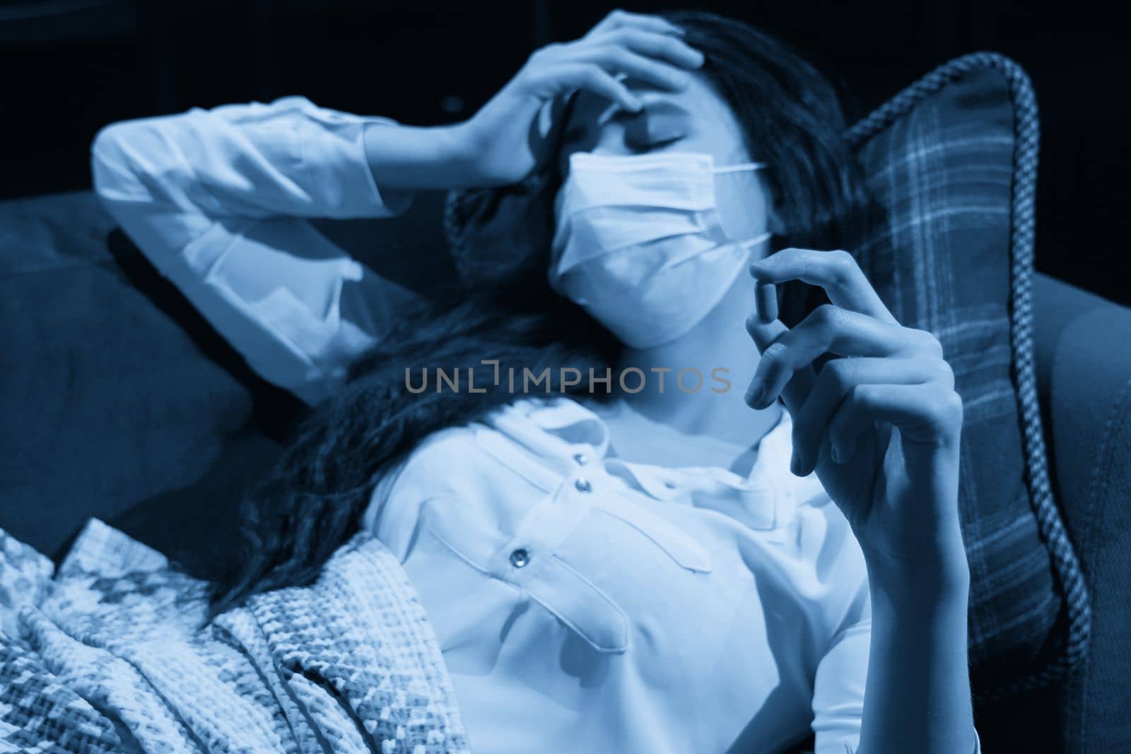 young woman on sofa covered with a blanket freezing blowing running nose got fever, caught, sick girl having influenza symptoms, flu or virus concept by Mariakray
