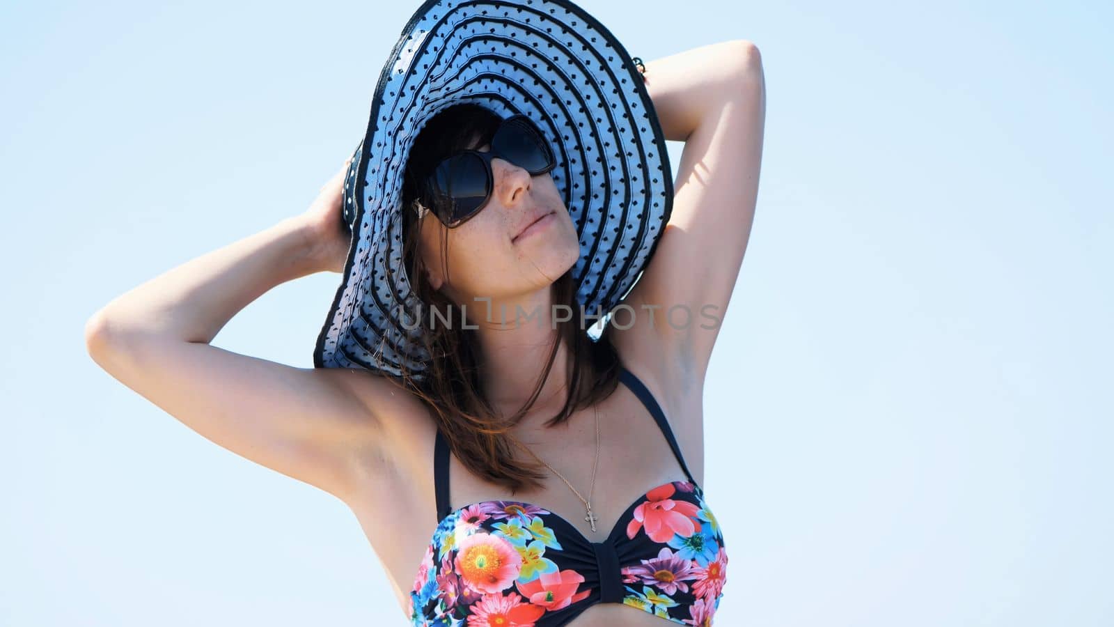 summer, sea, portrait of a beautiful young brunette woman wearing a bathing suit and sun hat, sunglasses, standing on a ferry deck, enjoying rest, beauty of the sea, happy, smiling. High quality photo