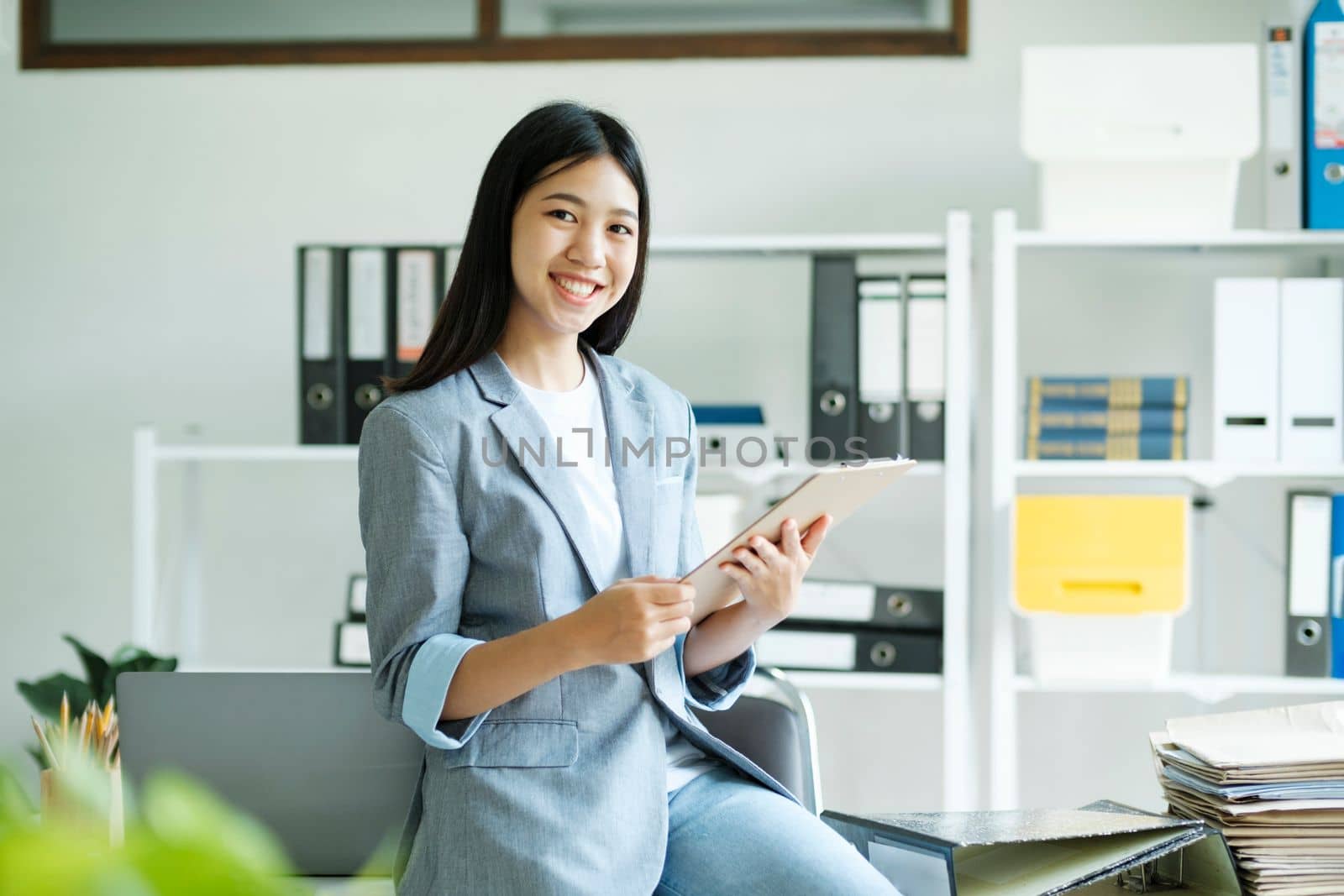 Young asian businesswoman uses a laptop to contact a customer, working hard at the office using laptop data graphs, planning for improvement, analyzing and strategizing for business growth. Business concept