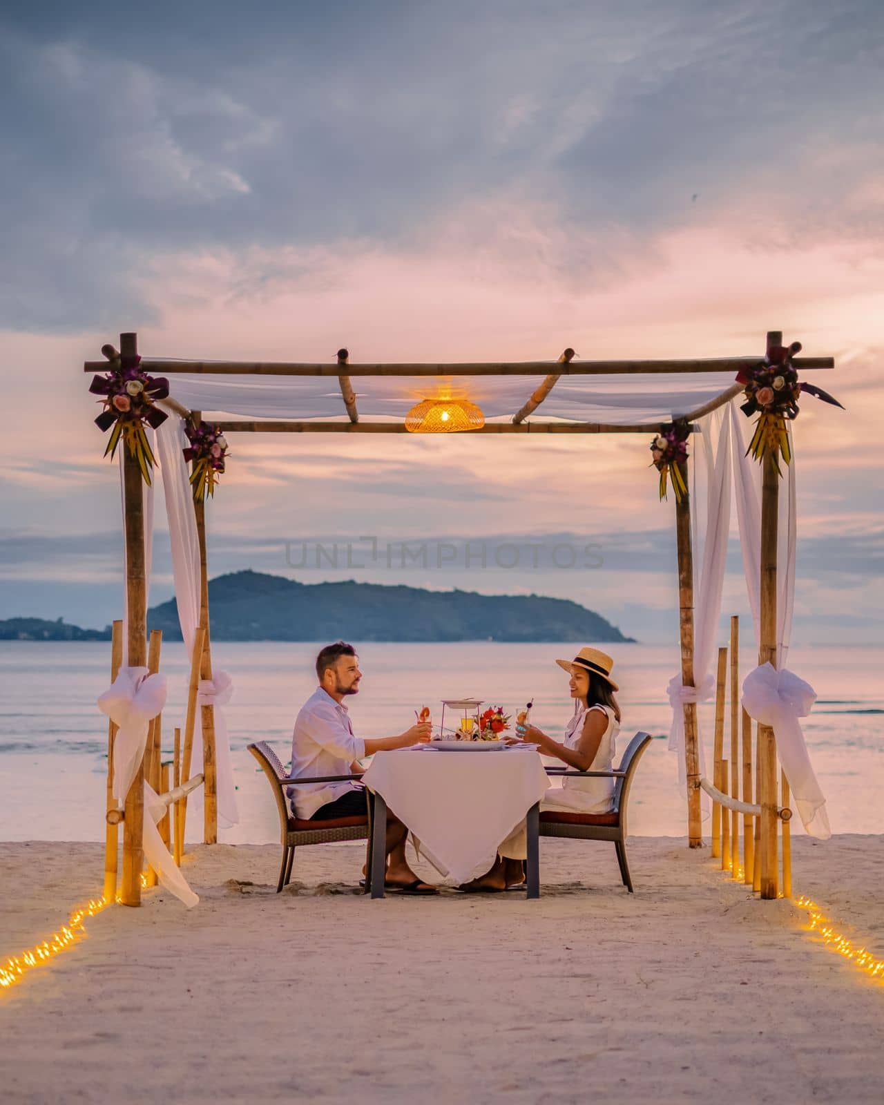 couple having a romantic dinner on the beach of Phuket Thailand during sunset 