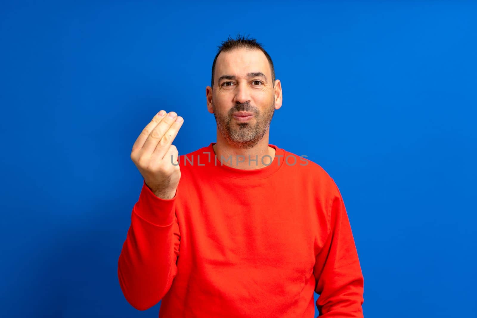 Handsome latino man with beard making a typical italian gesture, smiling and looking to the front, symbol or expression with his hand, very natural