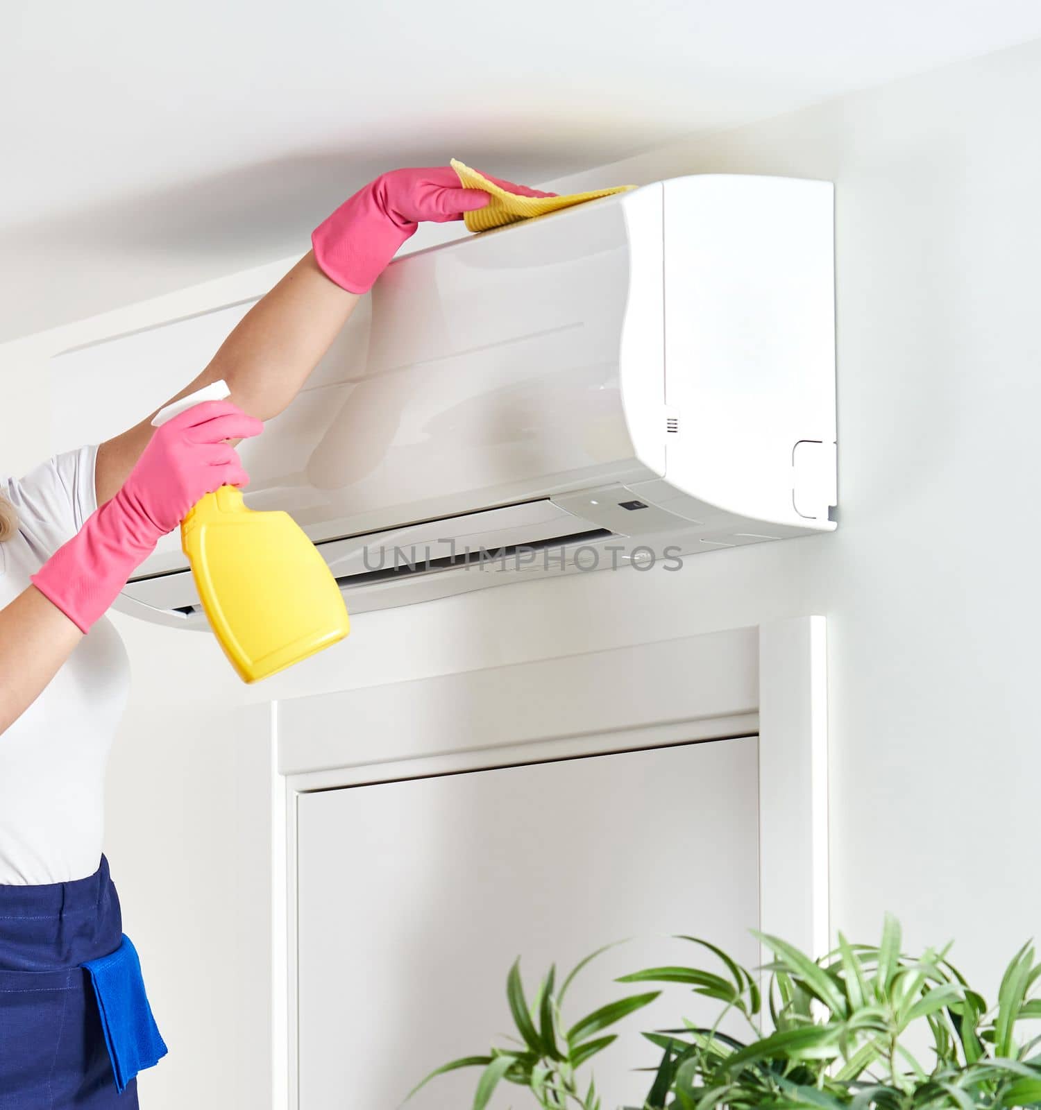 Woman cleaning air conditioner with rag. Cleaning service or housewife concept by Mariakray