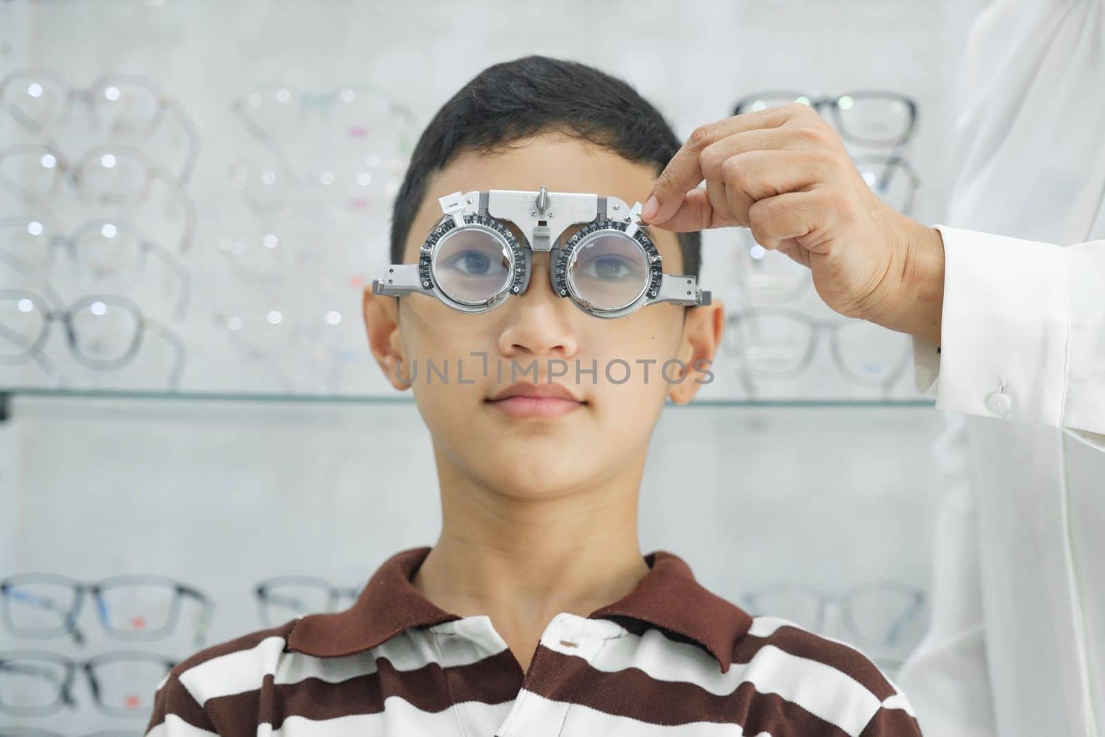 Young boy examining eyesight in optical clinic. by ijeab