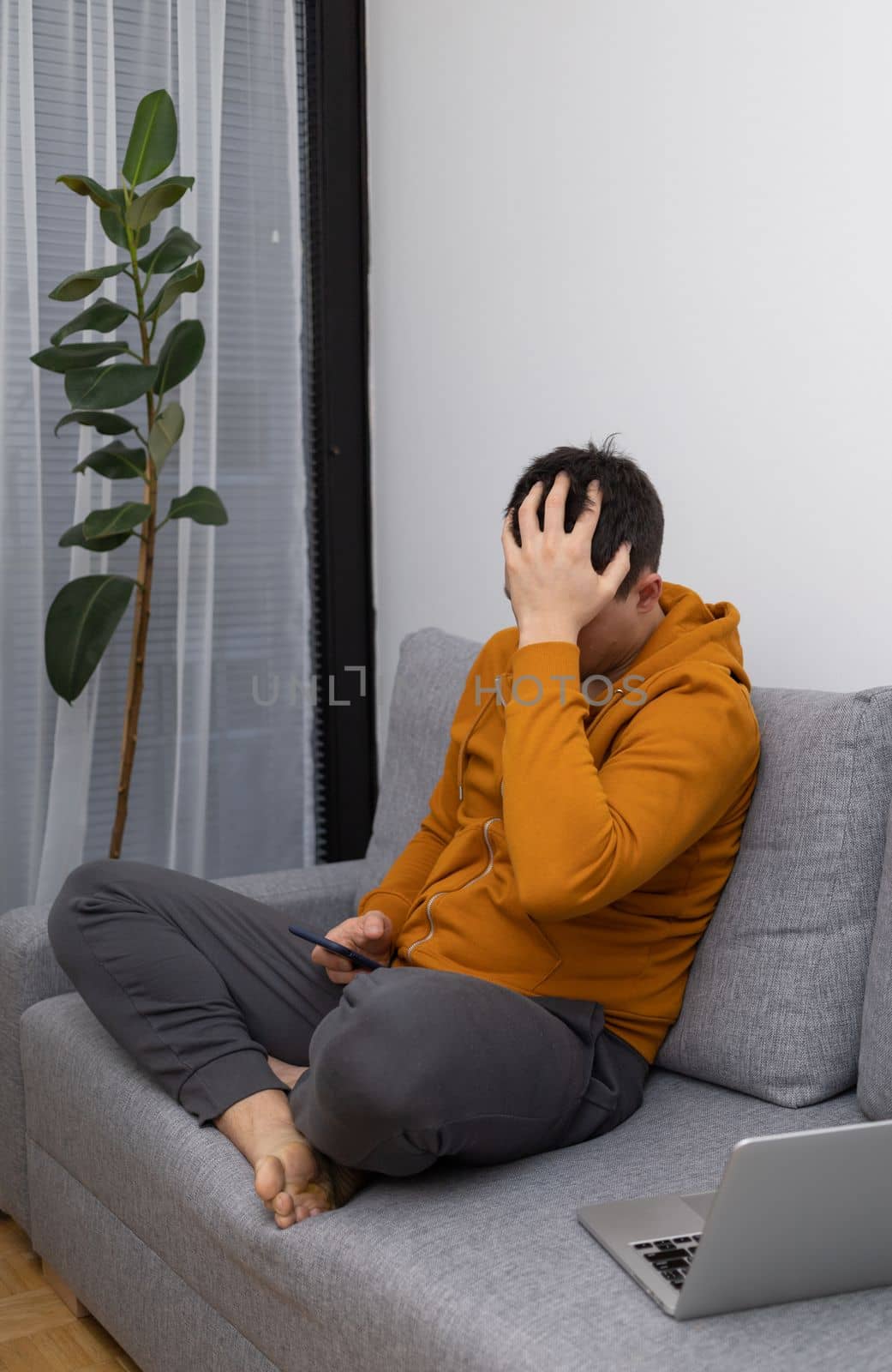 upset young man at home watching at mobile phone. High quality photo