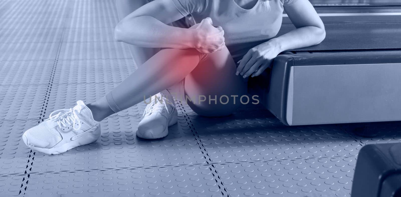 Young woman in sportswear having ache in knee while training in gym, Girl sitting on a floor touching her knee in pain by Mariakray