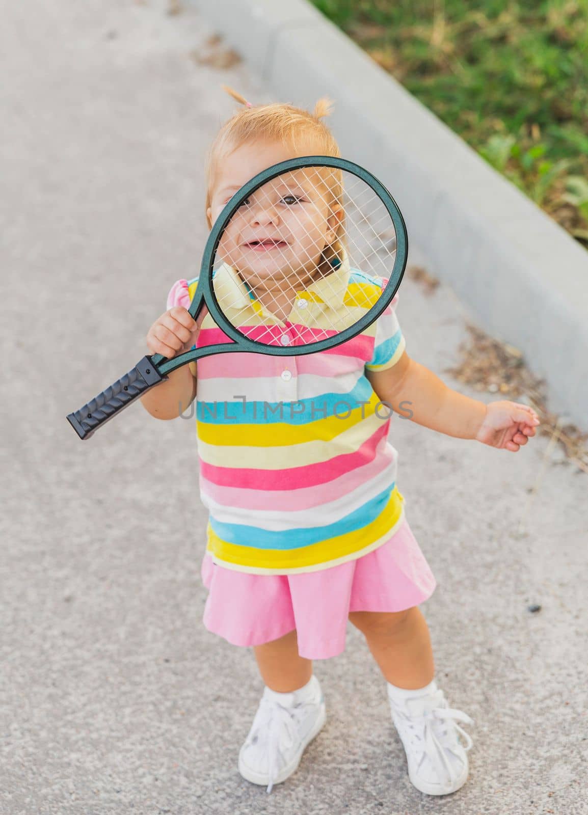 charming little tennis player covered by racket.