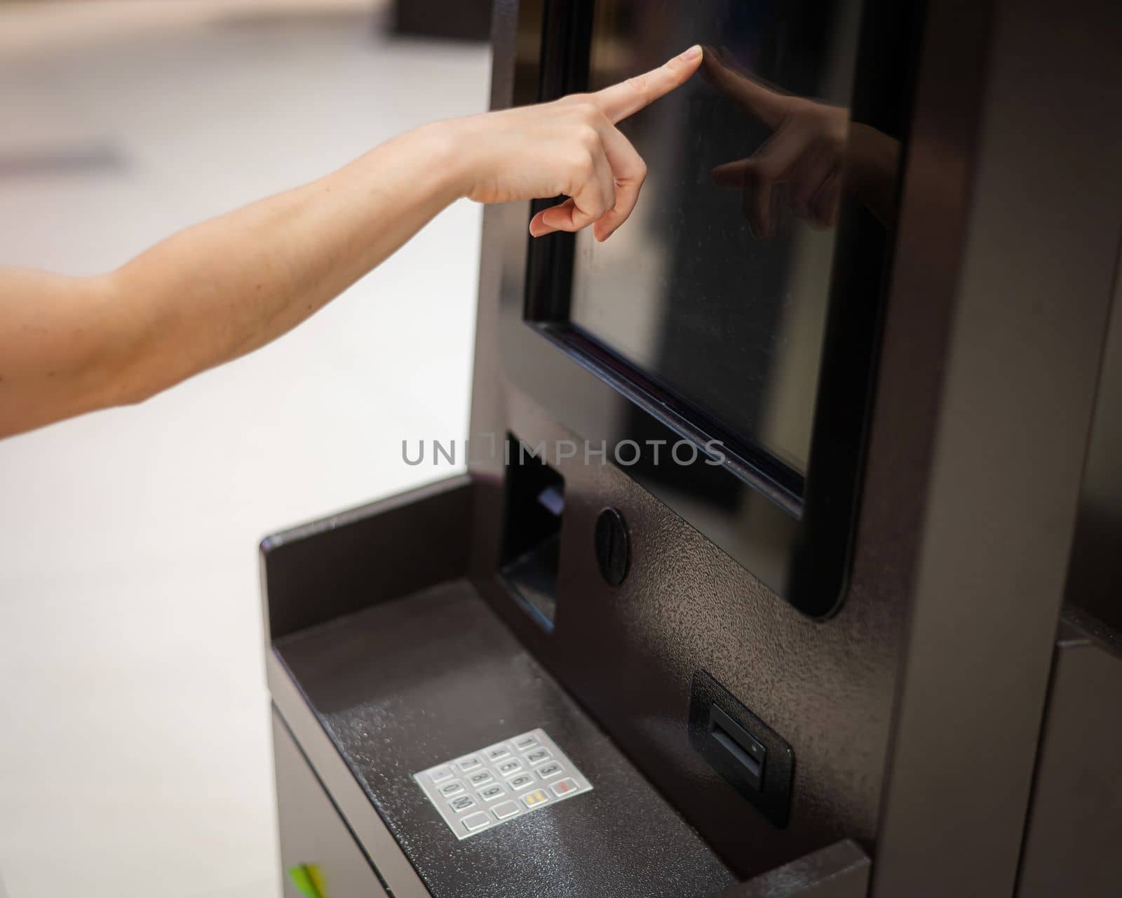 Faceless woman using touchscreen ATM