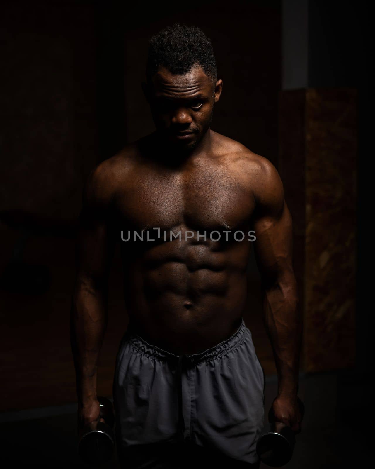 Muscular dark-skinned man doing an exercise with dumbbells. by mrwed54