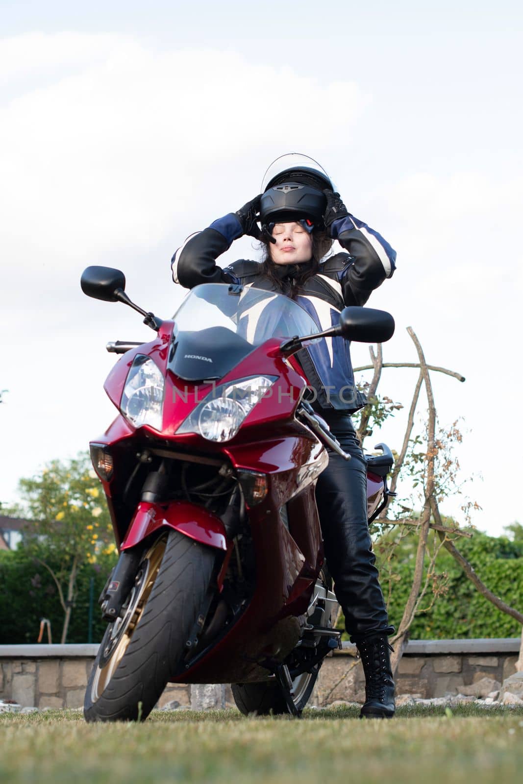 young beautiful brunette blogger on a motorcycle puts on a helmet, As,Belgium, May 16,2022, High quality photo