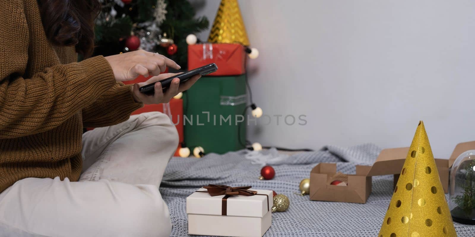 Close up overjoyed asian woman using phone, celebrating success, showing yes gesture, sitting on Christmas tree background at home, received great news, shopping sale, reading message..