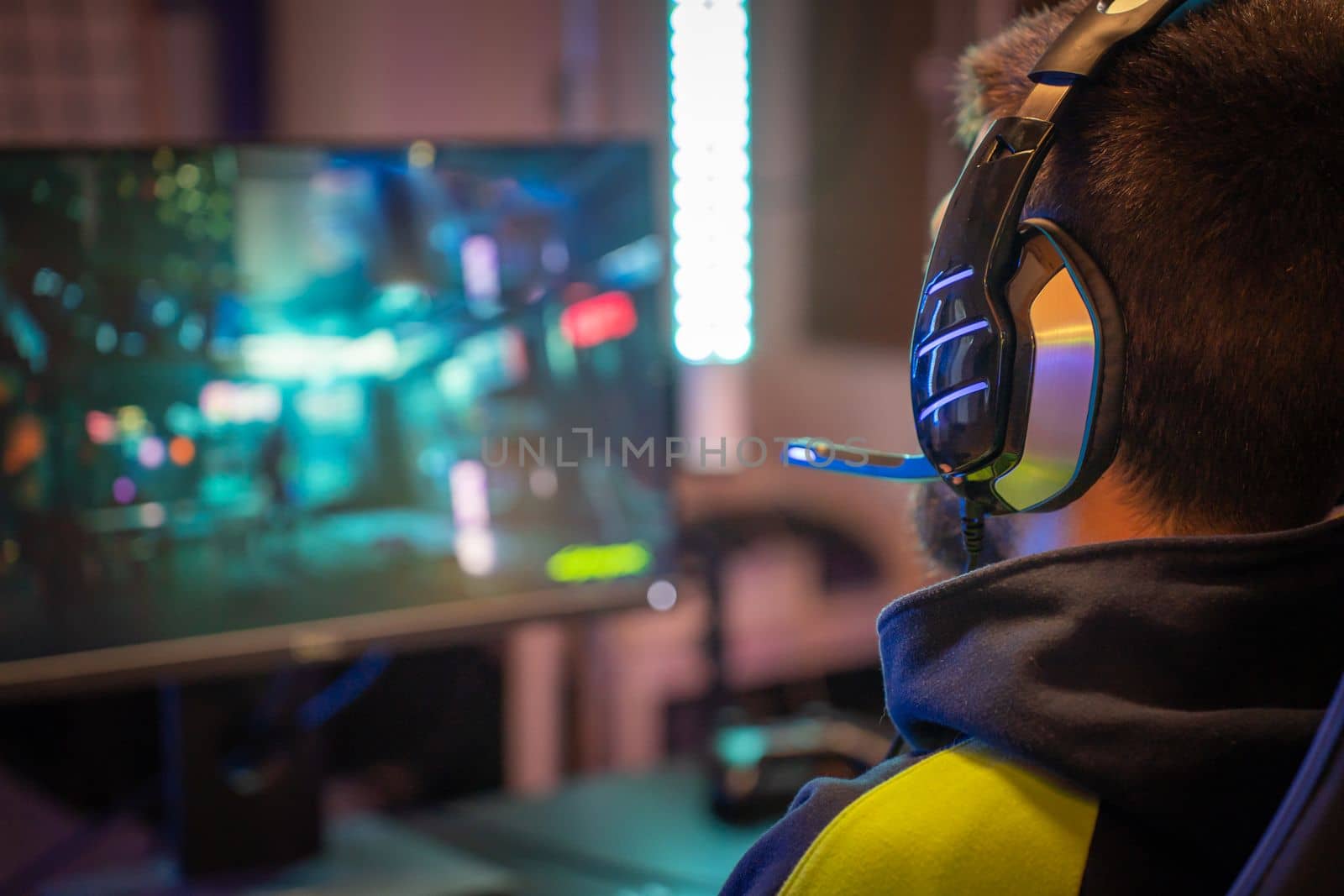 Rear view of young guy wear headphones play videogame weekend sports hobby indoors by PaulCarr