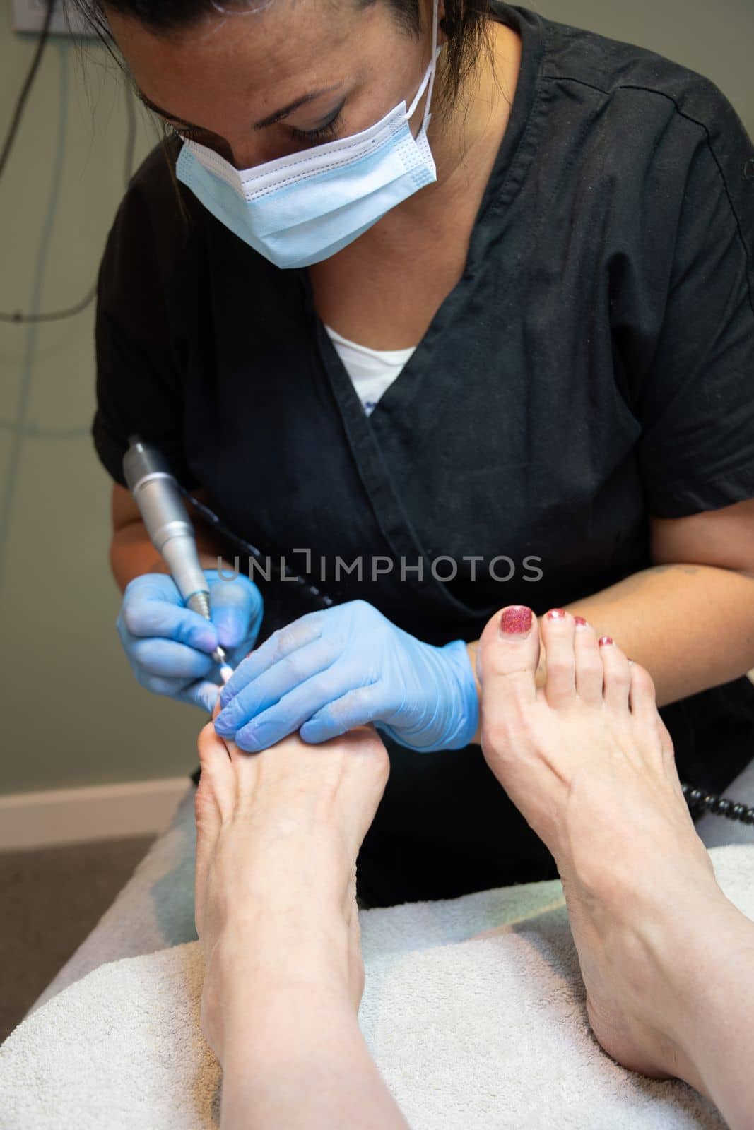 A master in a beauty salon makes a hardware pedicure to a client, Fraser removal of red varnish and cuticles. Close-up, soft focus. High quality photo