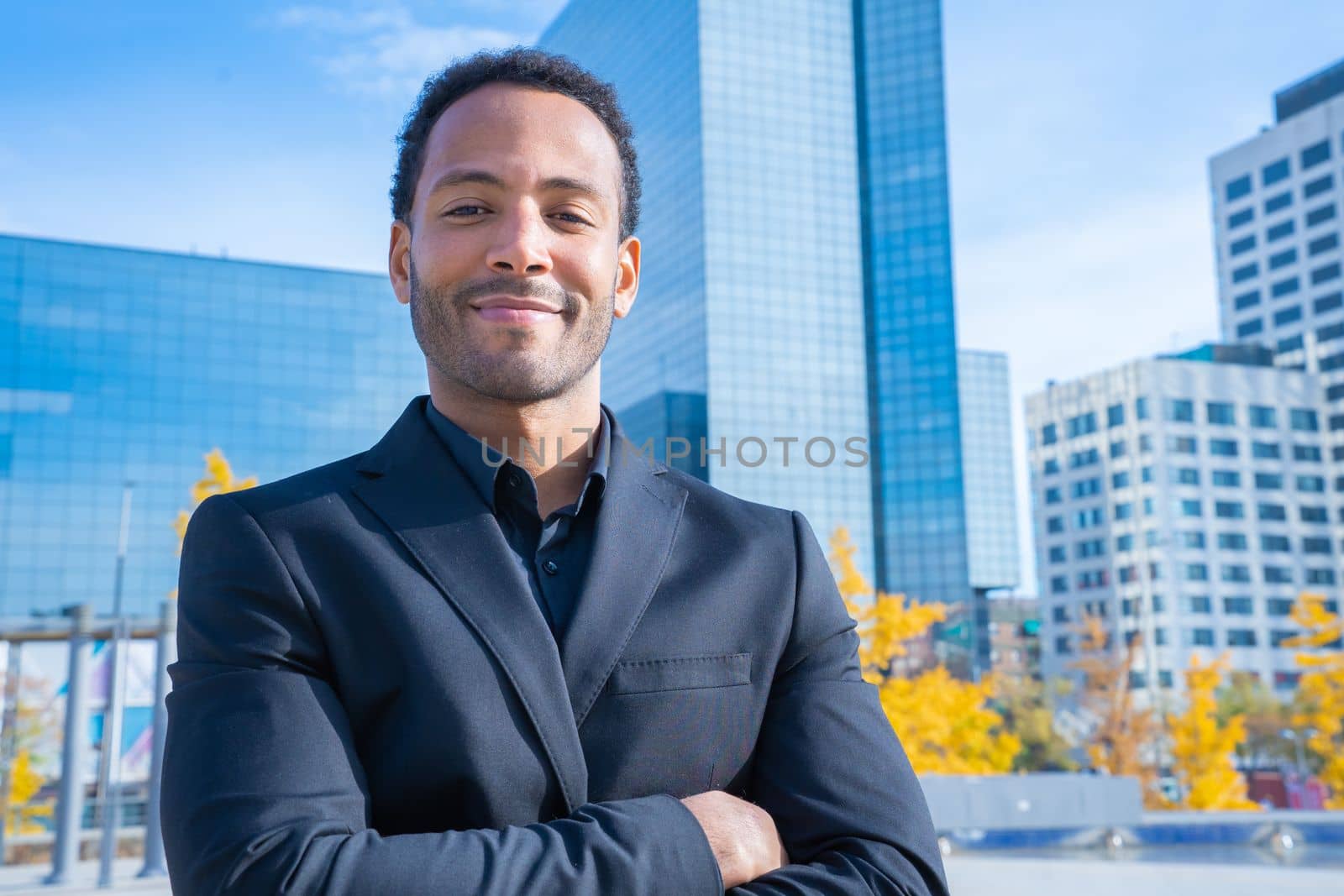 Portrait of successful smiling African American businessman in suit smiling looking at camera with financial buildings in background. Confident CEO black male happy. Business concept. High quality photo