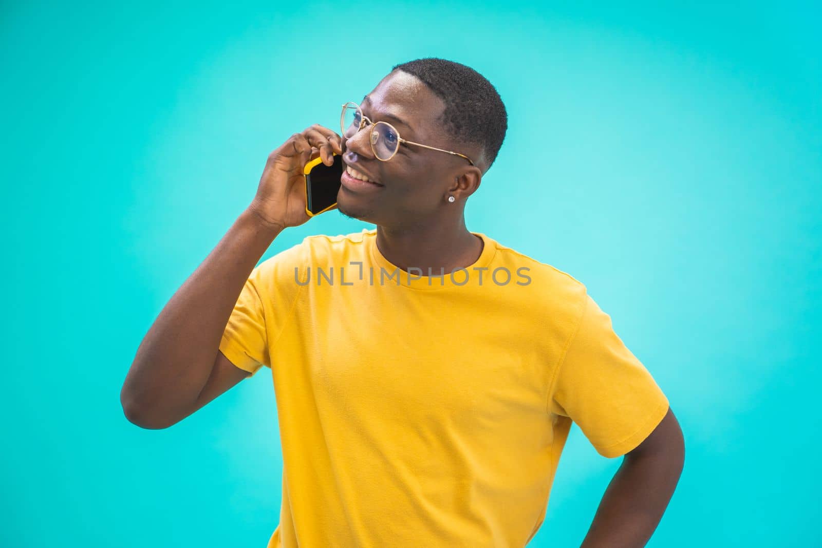 Attractive black guy African talking on the cellphone happy smiling isolated on blue background. Concept of success, student with a smartphone. High quality photo