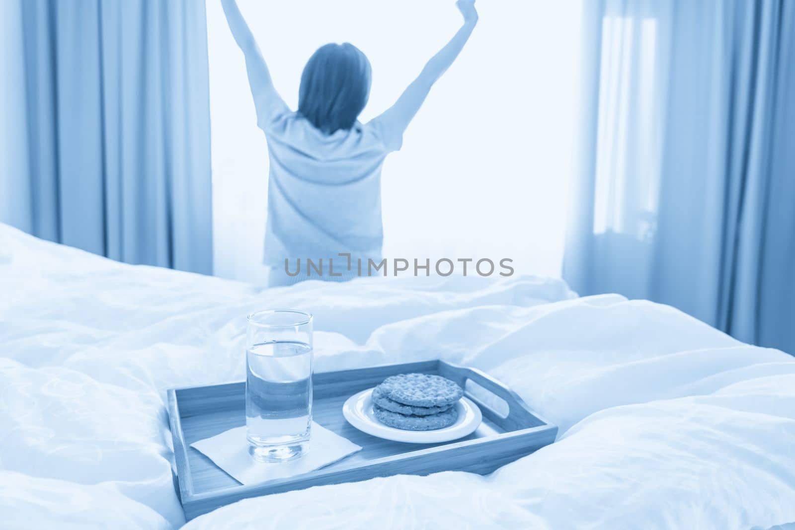 Tray with diet breakfast on a bed with woman stretching on background by Mariakray