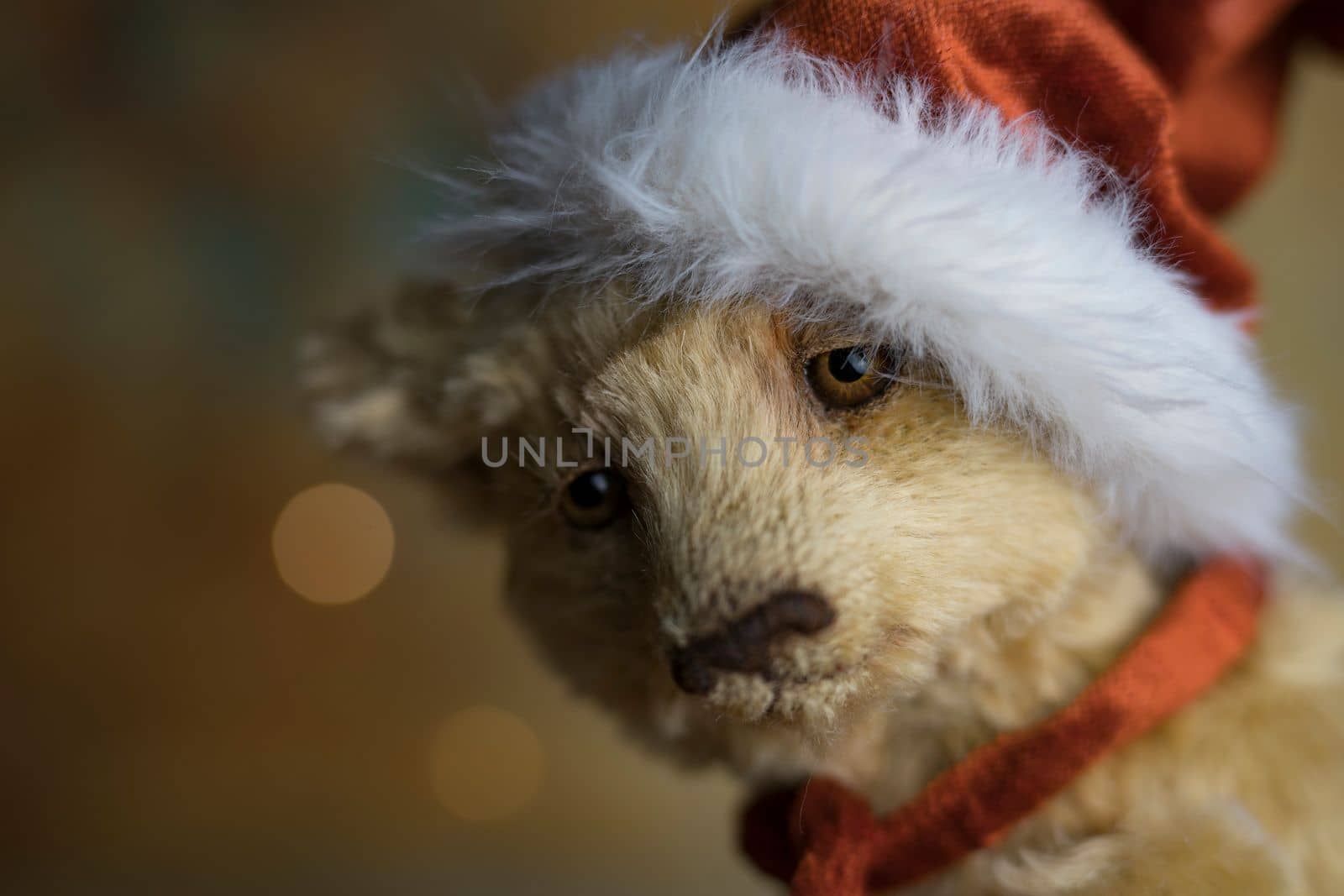 Christmas card greeting with cute handmade teddy bear with red Santa cap on brown background by Costin