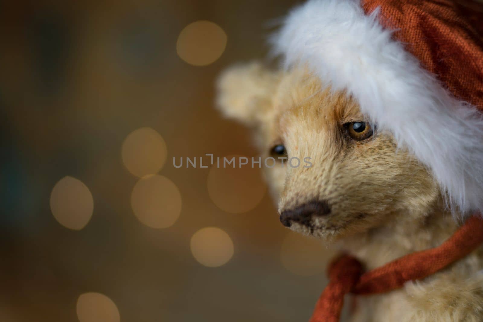 Christmas card greeting with cute handmade teddy bear with red Santa cap on brown background by Costin