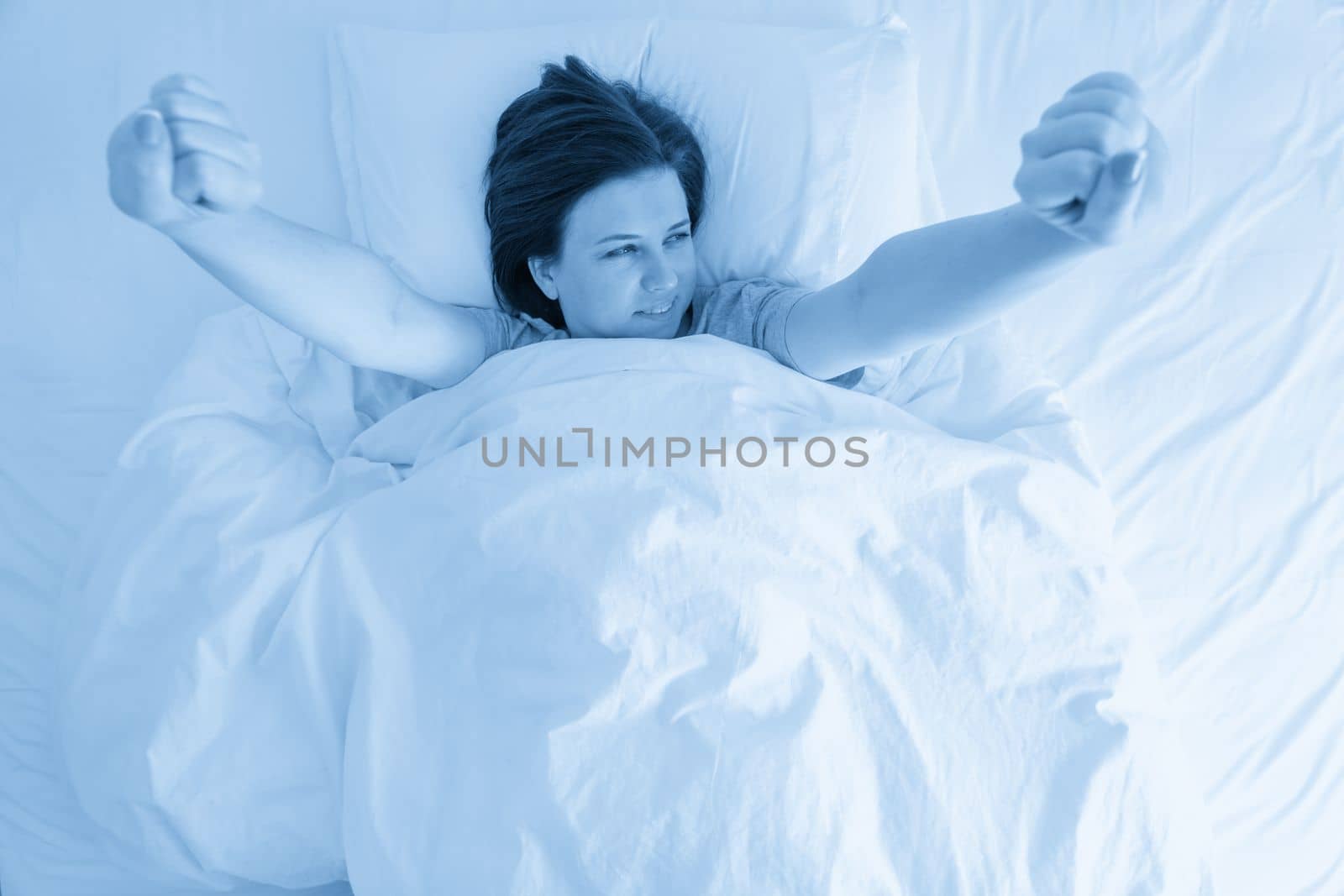 Young wonam stratching in bed after sleeping by Mariakray