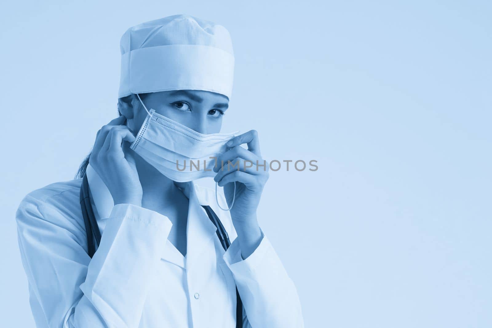 portrait of female doctor wearing protective mask and looking at camera posing against white background, copy space