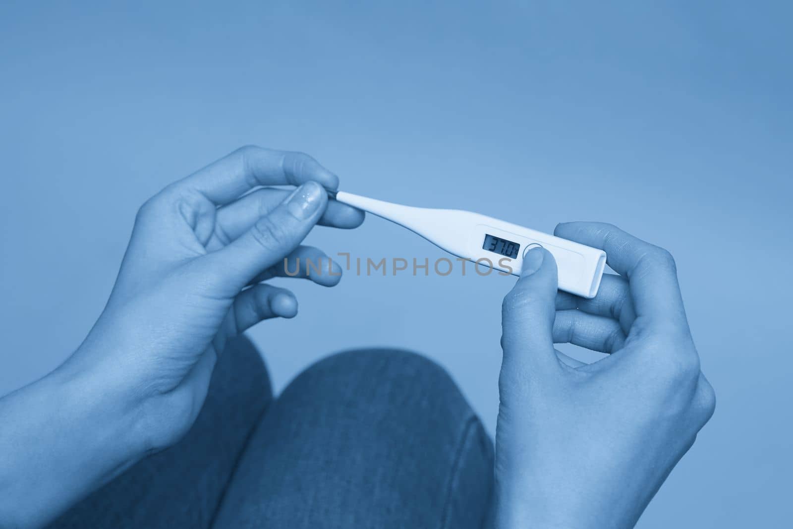 Woman looking at thermometer. Female hands holding digital thermometer. Concept of fever, flue or virus