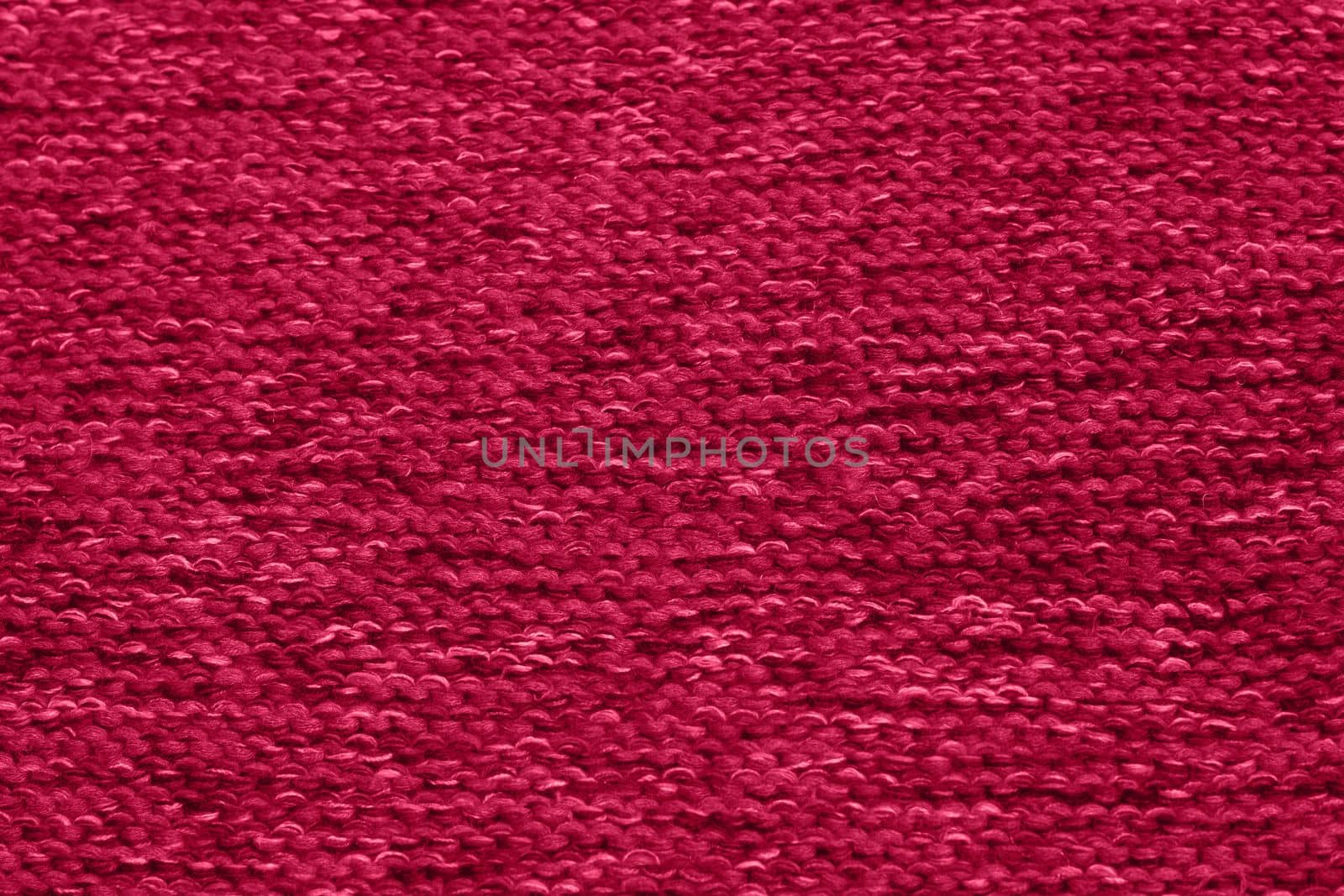 Viva Magenta toned colour monochrome texture knitted fabric. Dark pink knitted Jersey as textile background. Monochrome color background. Trendy color 2023.