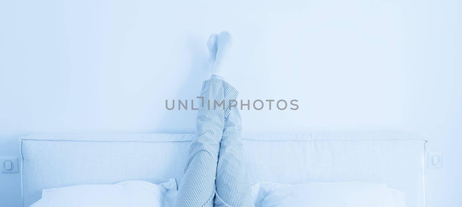 Panorama of female legs raised up high lying on bed