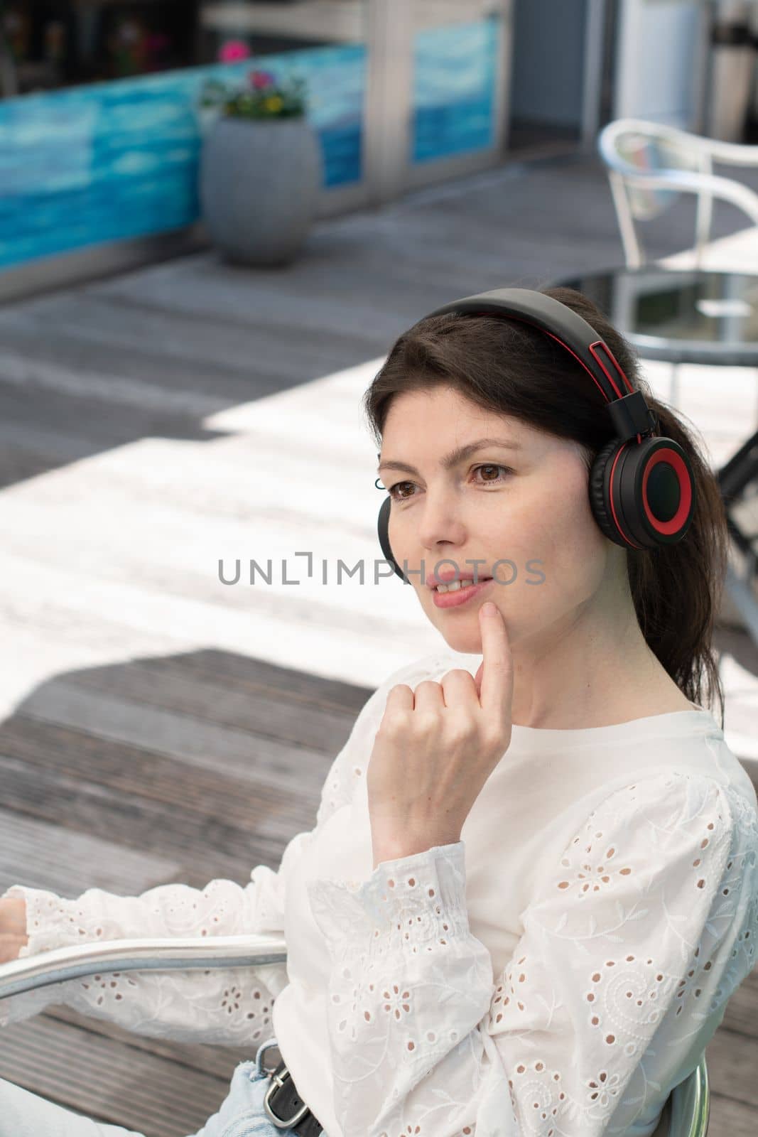 Sad girl listens to music from a tablet at a table in a cafe, High quality photo