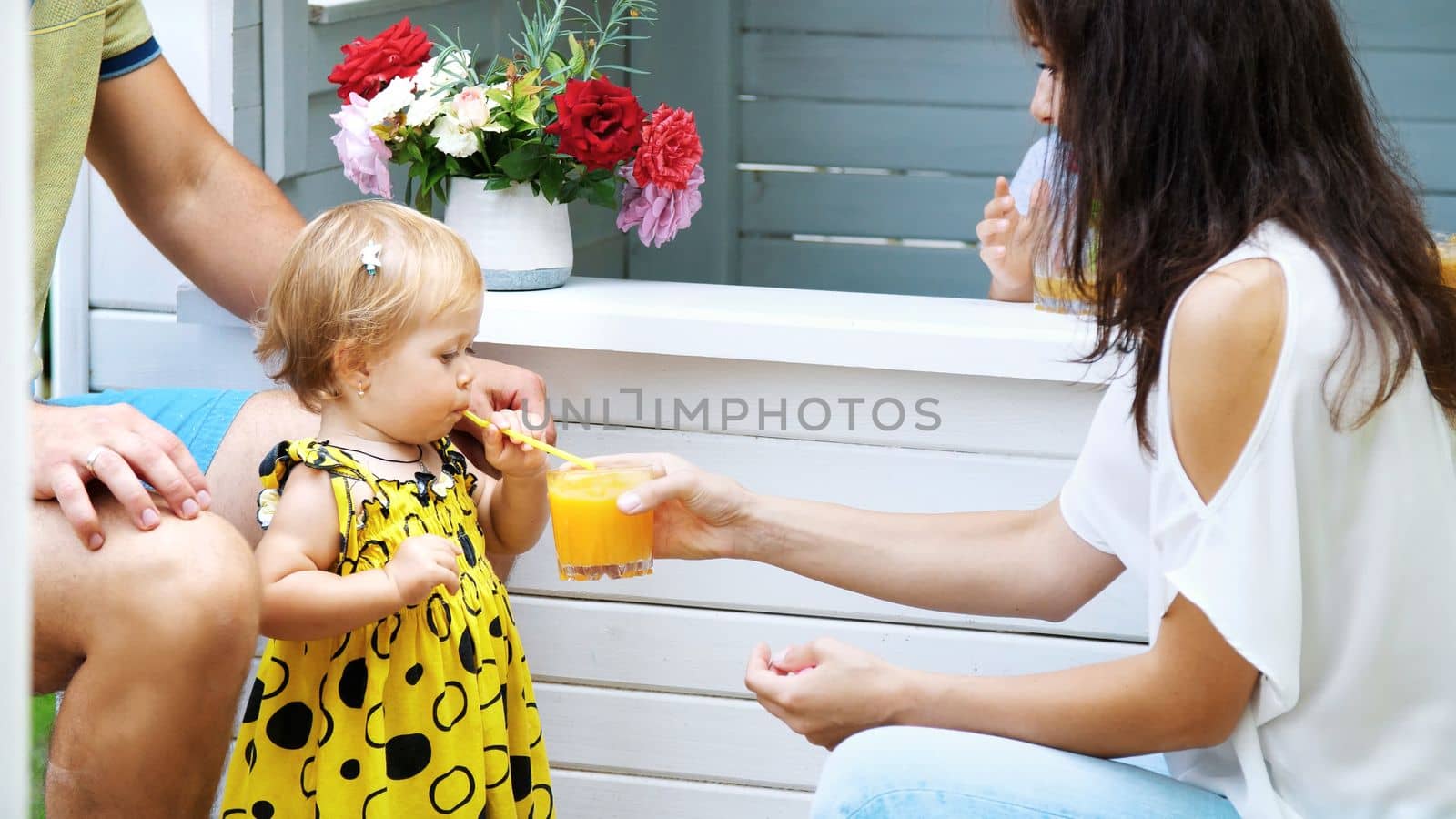 summer, in the garden, parents play with young children, a girl and a boy, in a cafe, in a children's play house, treat children with freshly squeezed fruit juices, drink juices. High quality photo
