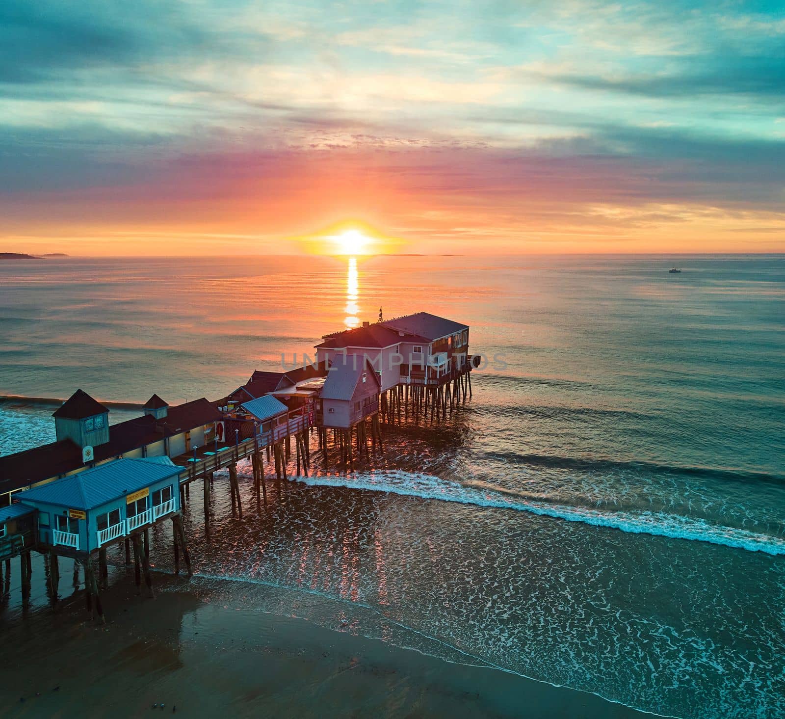 Image of Golden sunrise over Maine ocean coast with old wood pier covered in shops