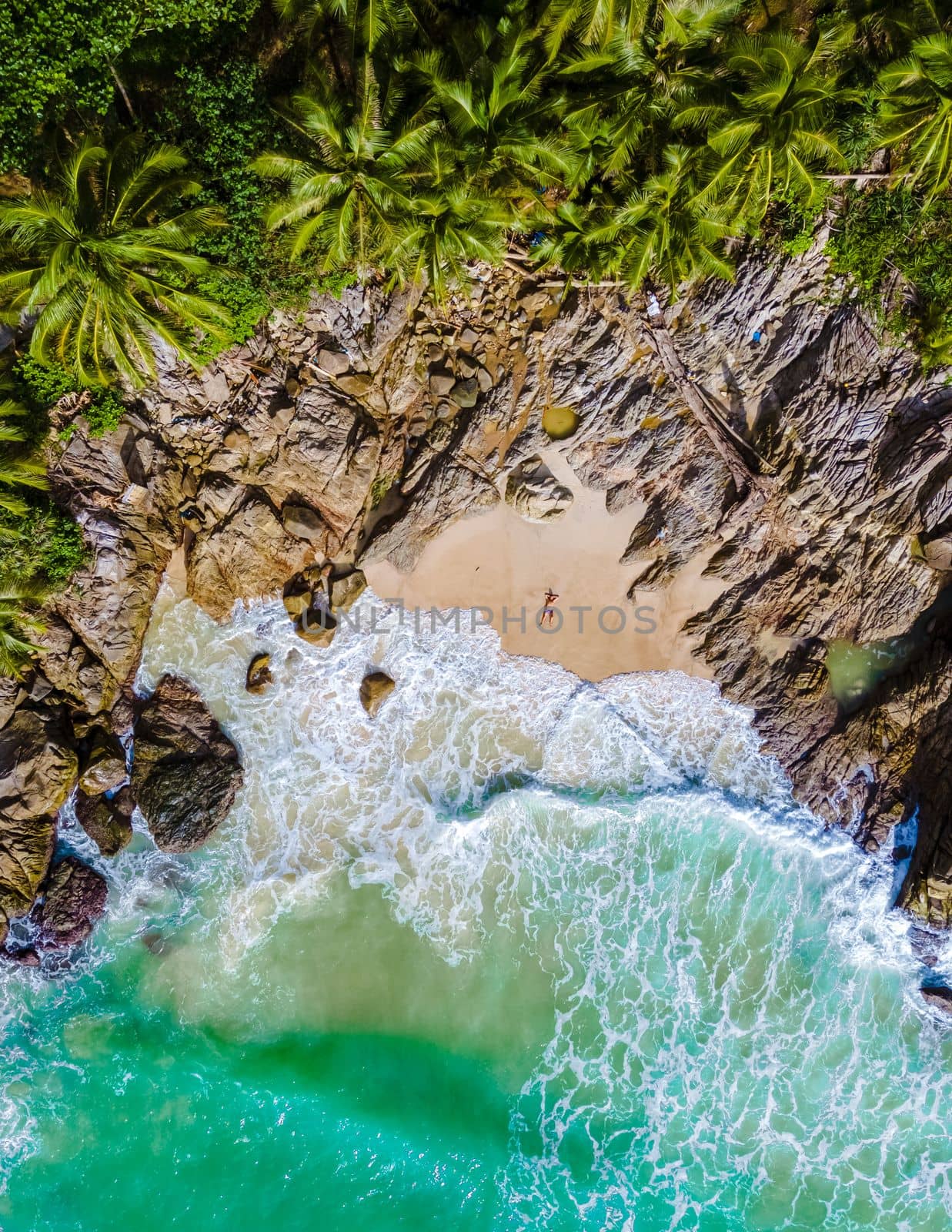 Drone aerial view at Freedom beach in Phuket Thailand, men laying down on beach in bay by fokkebok