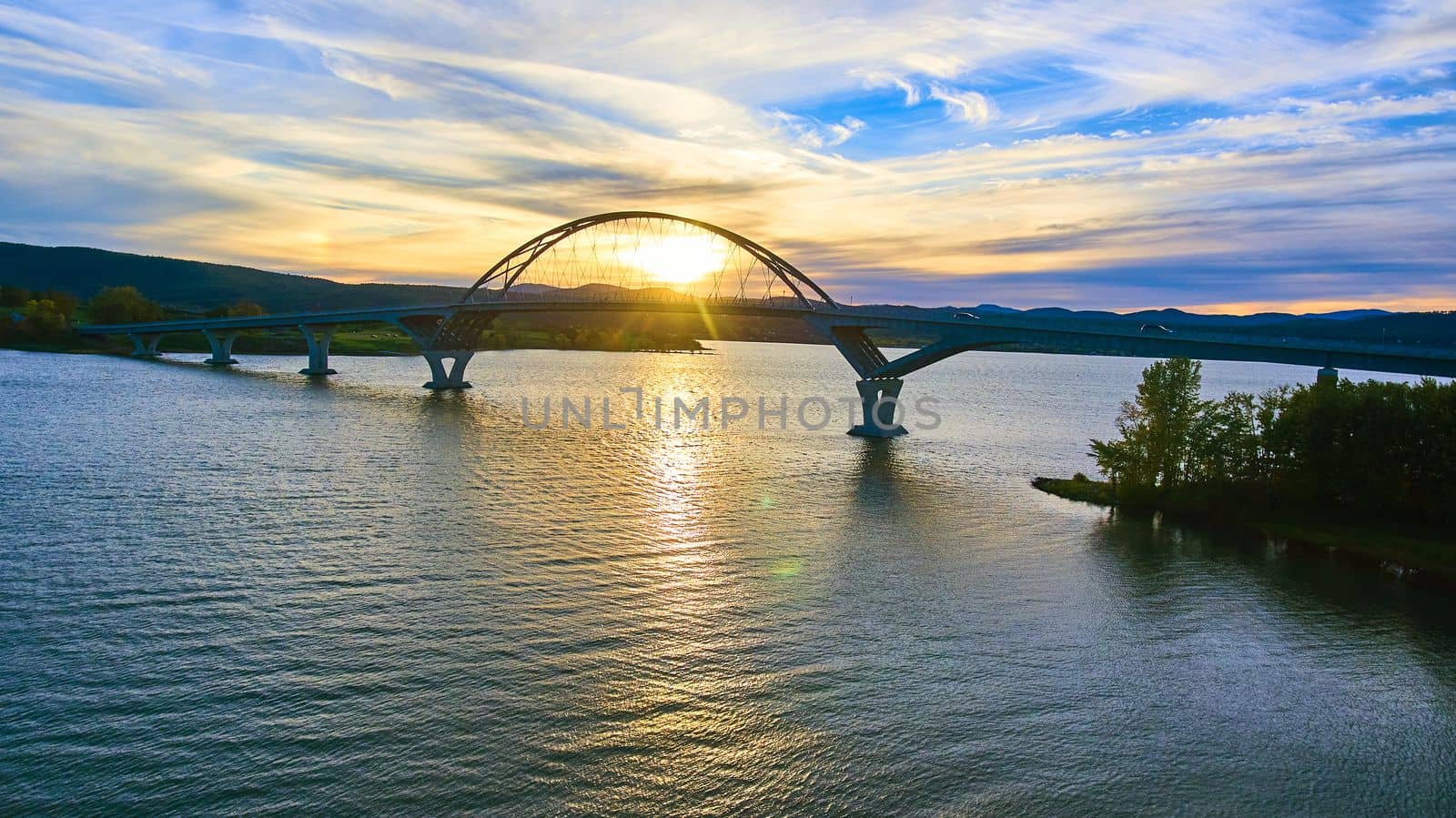 Image of Aerial of bridge with sun in arch during sunset connecting New York to Vermont