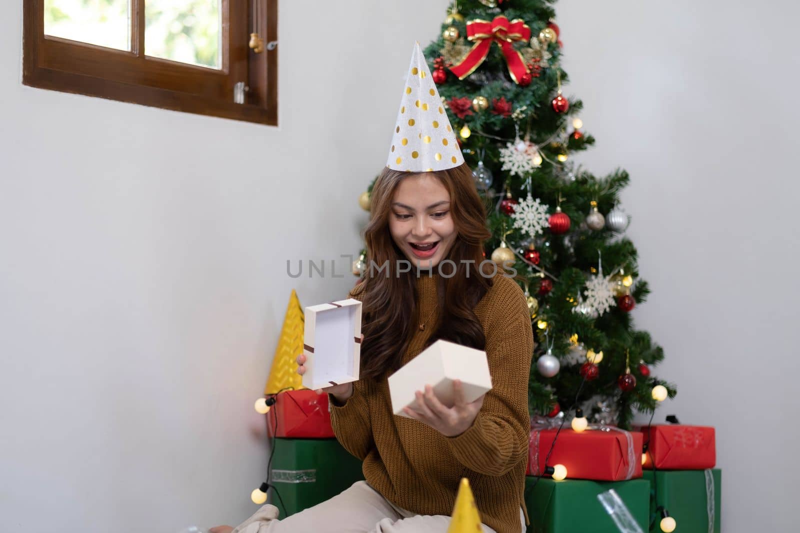 Merry Christmas and Happy Holidays Young woman with a beautiful face in a yellow shirt shows joy with gift boxes in a house