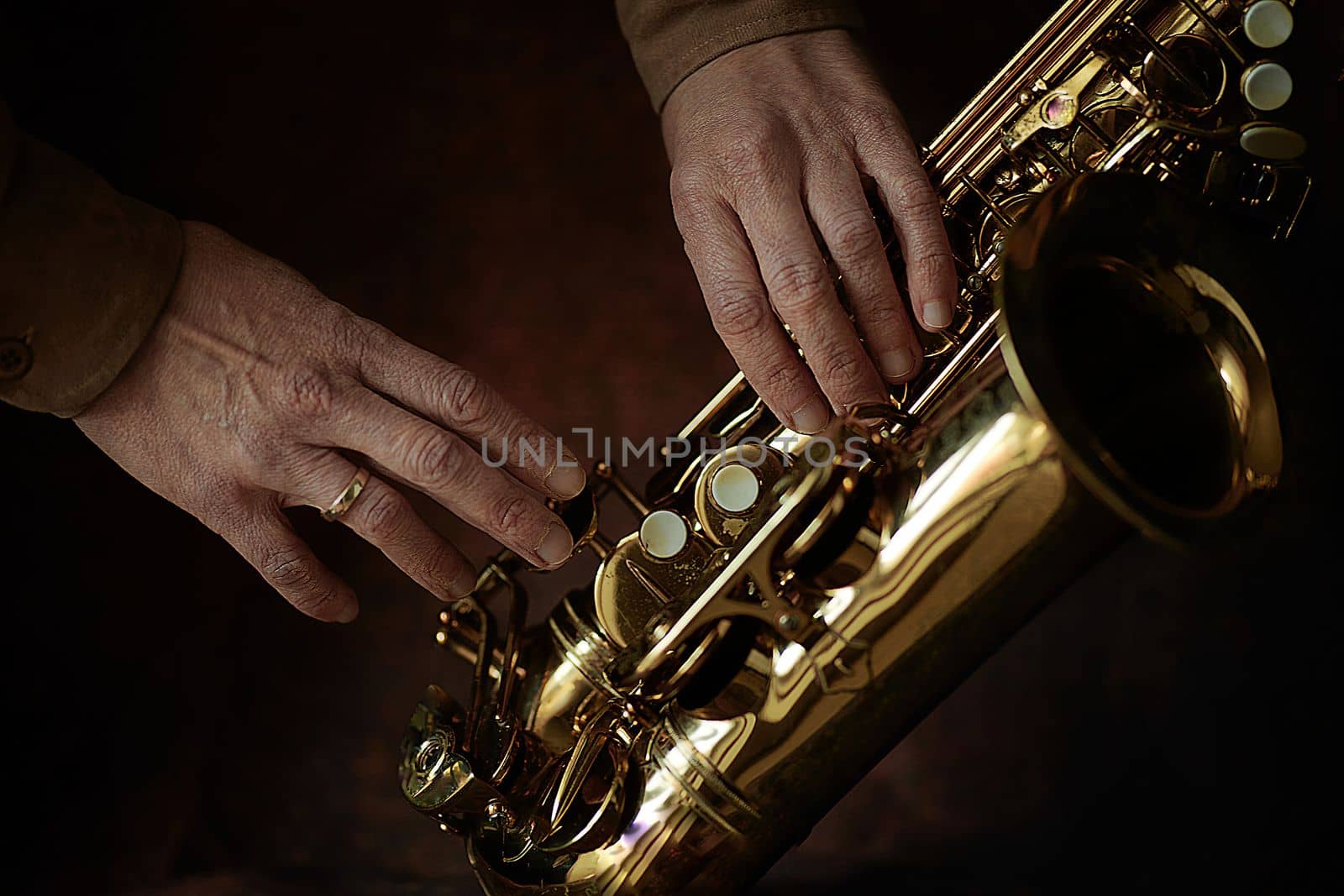 the hands of a musician on the saxophon - an ancient musical wooden instrument popular in classical brass marching jazz folk music, loved by children and adults, amateurs and professionals. by Costin