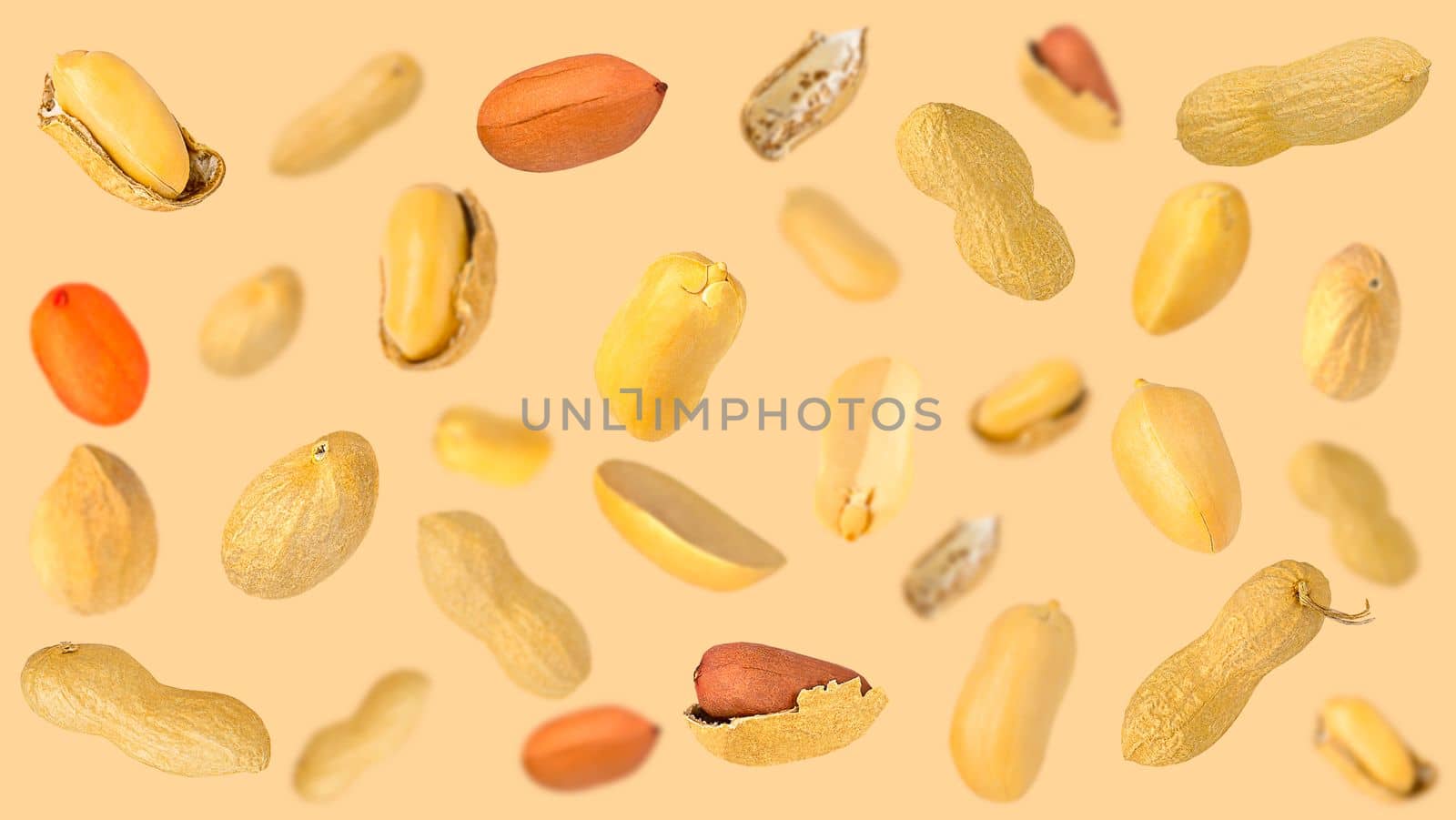 Creative levitation peanut pattern on a light pastel beige background with peeled and unpeeled beans. Flat lay creative arrangement. Selective focus