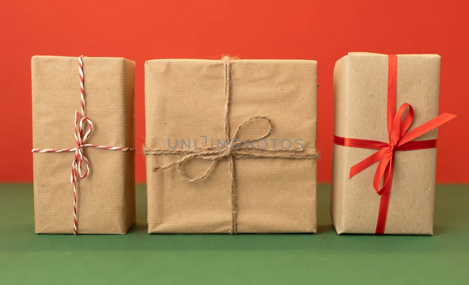 three craft wrapped gifts over red background by Chechotkin