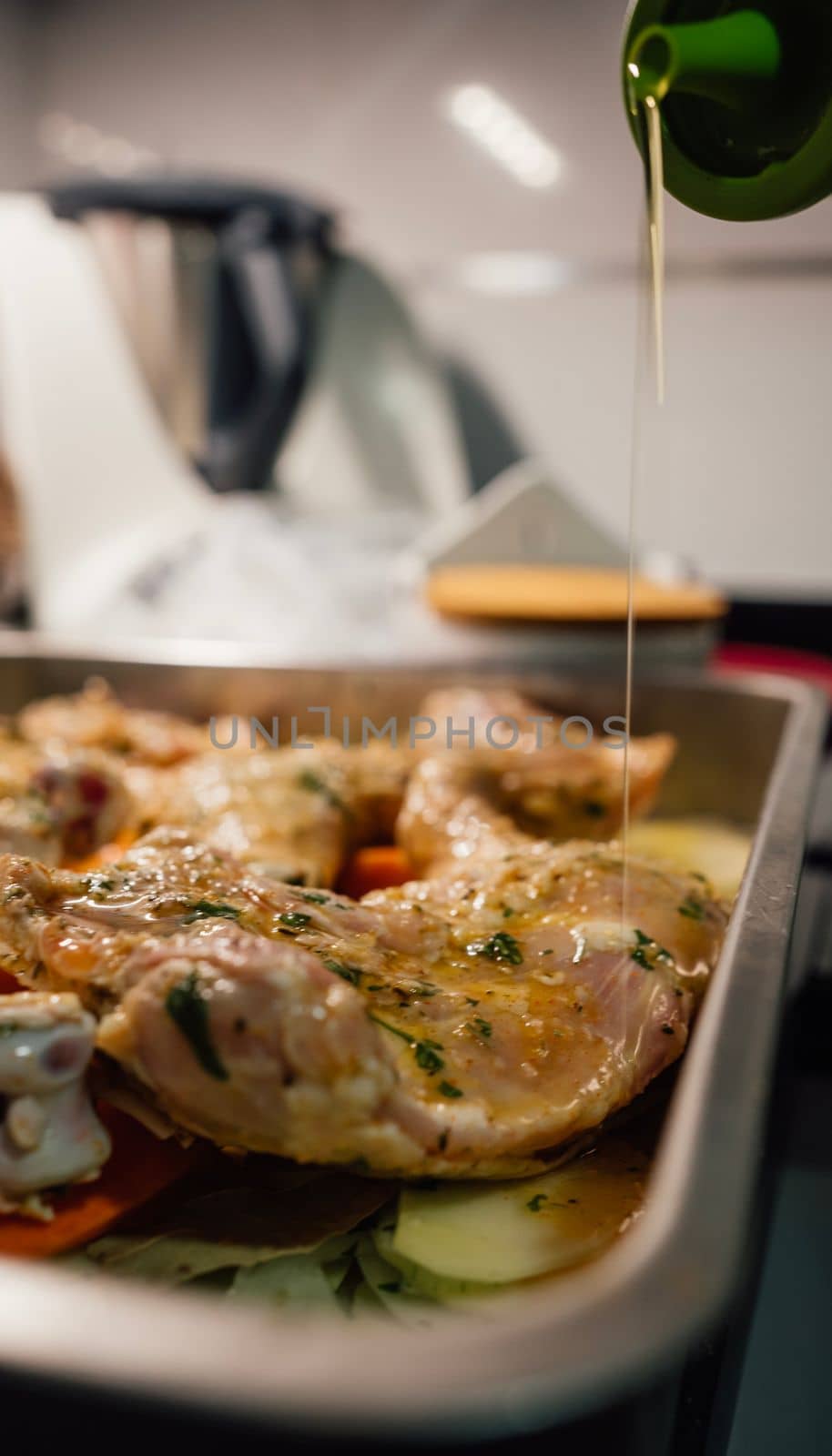 Chef pouring olive oil on chicken breasts preparing it for baking